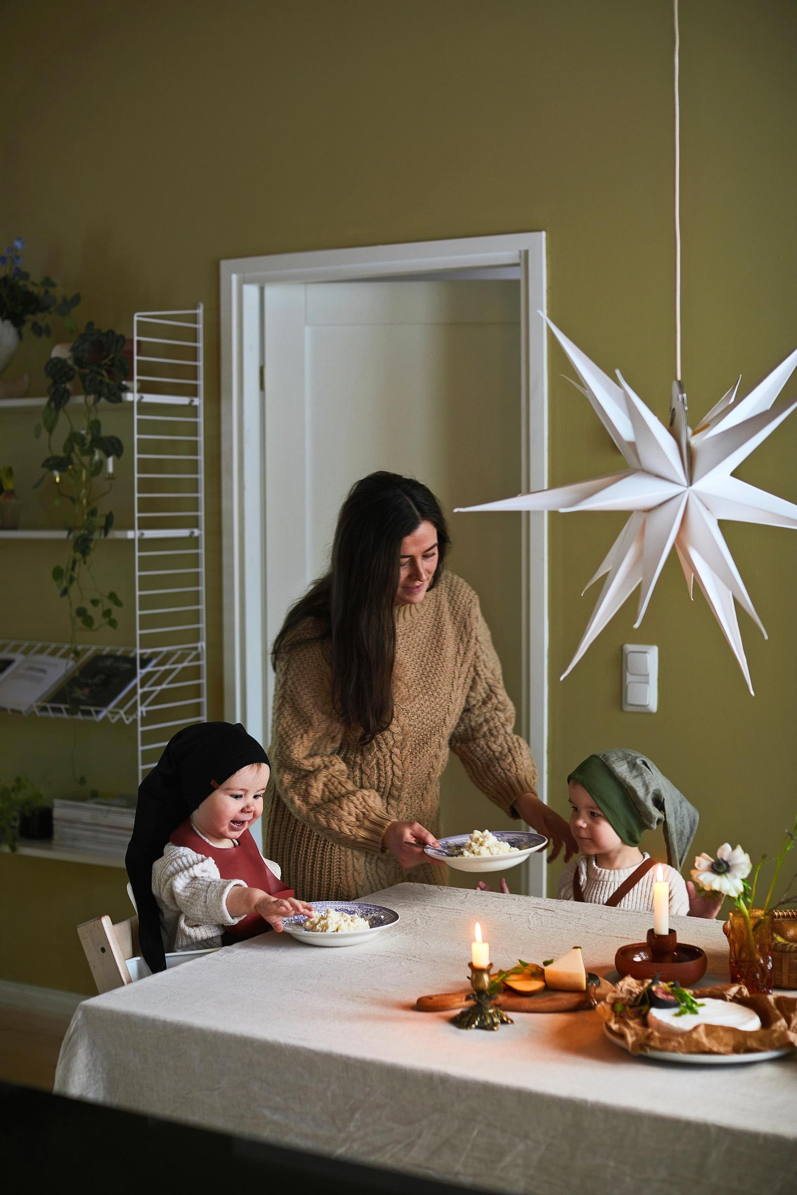 Jade Anetjärvi serves porridge to her son, with Jose and Jens sitting at the table. Christmas table setting and a paper star are also visible.