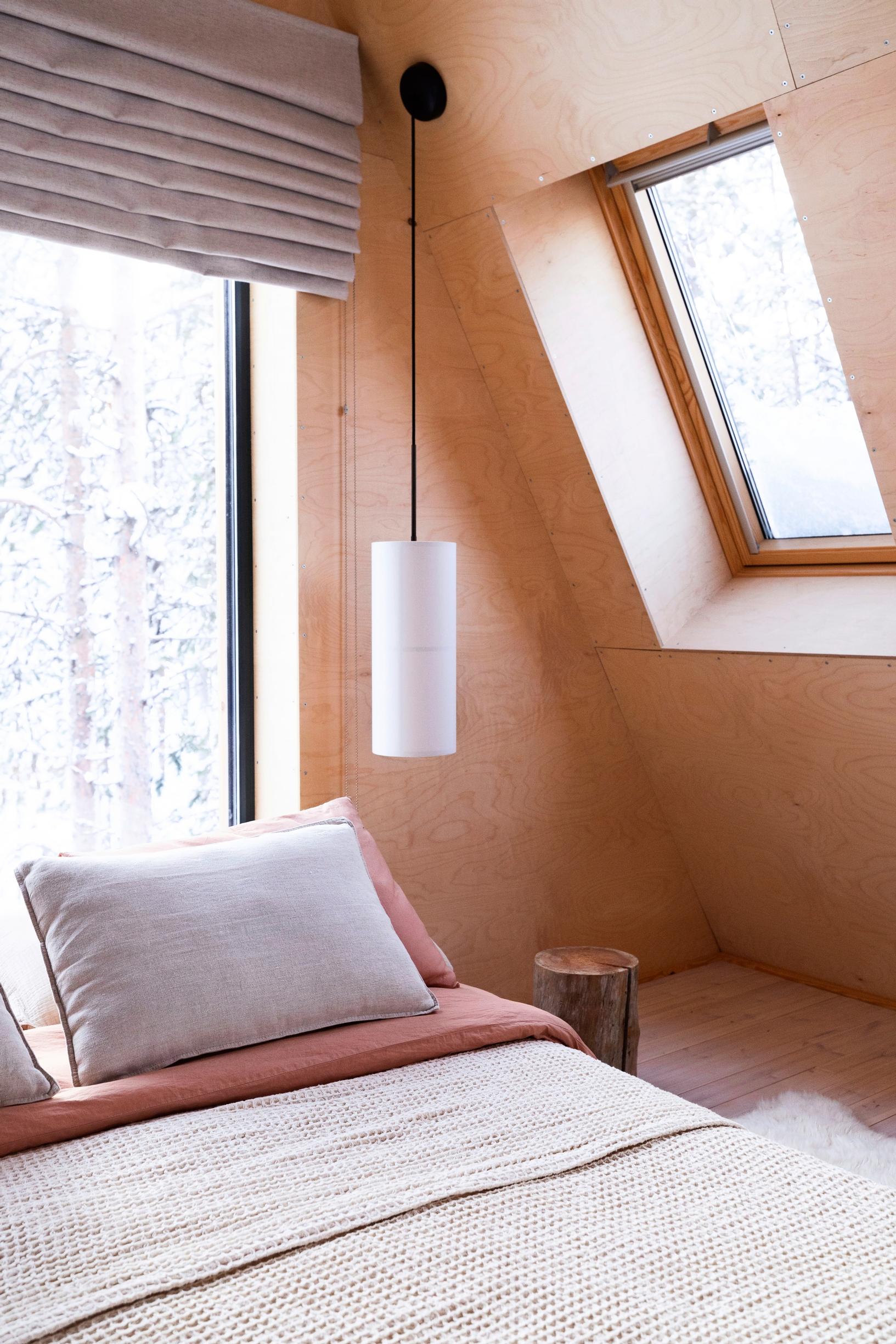 Bed surrounded by windows and a modern pendant lamp