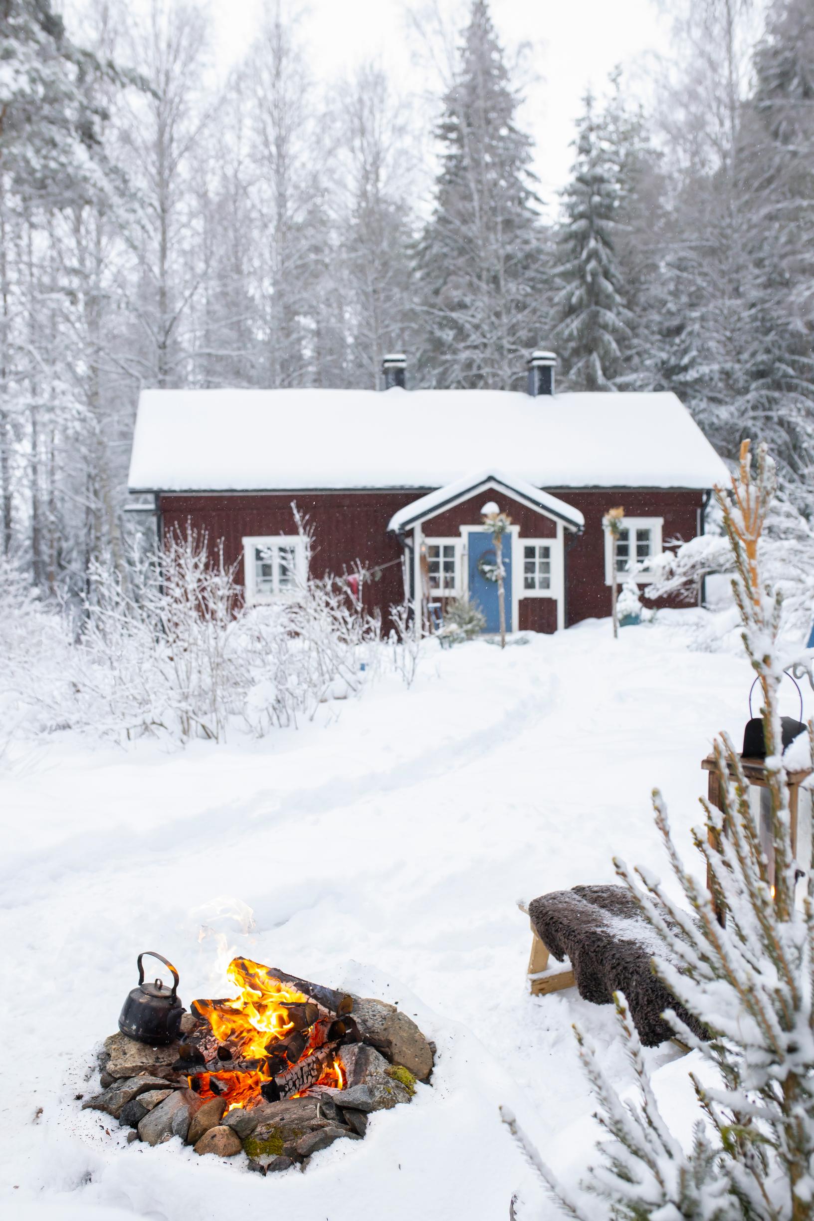 A campfire in the yard of the red cottage in winter.