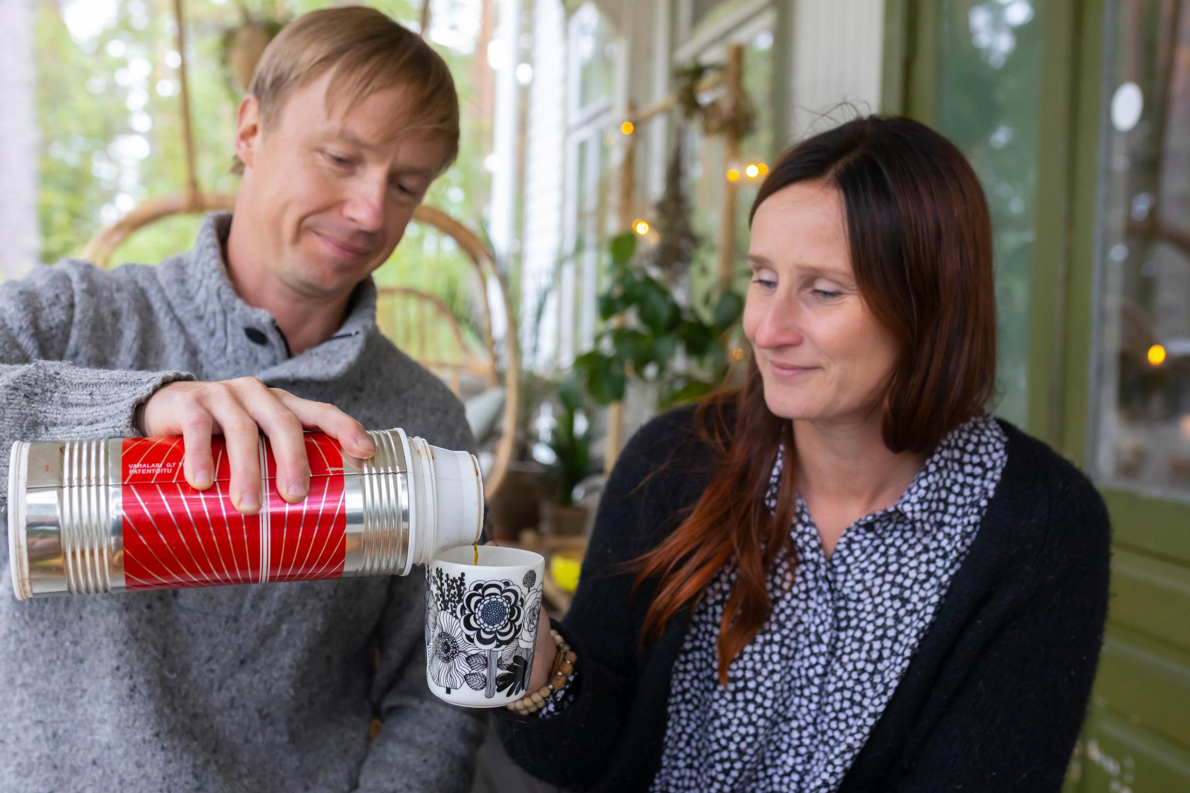 Man pouring coffee from a thermos for a woman on the terrace.