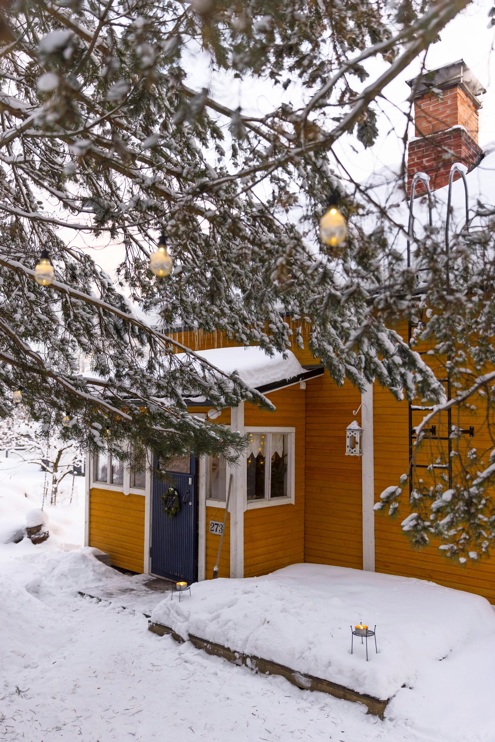 A yellow wooden house in a snowy setting