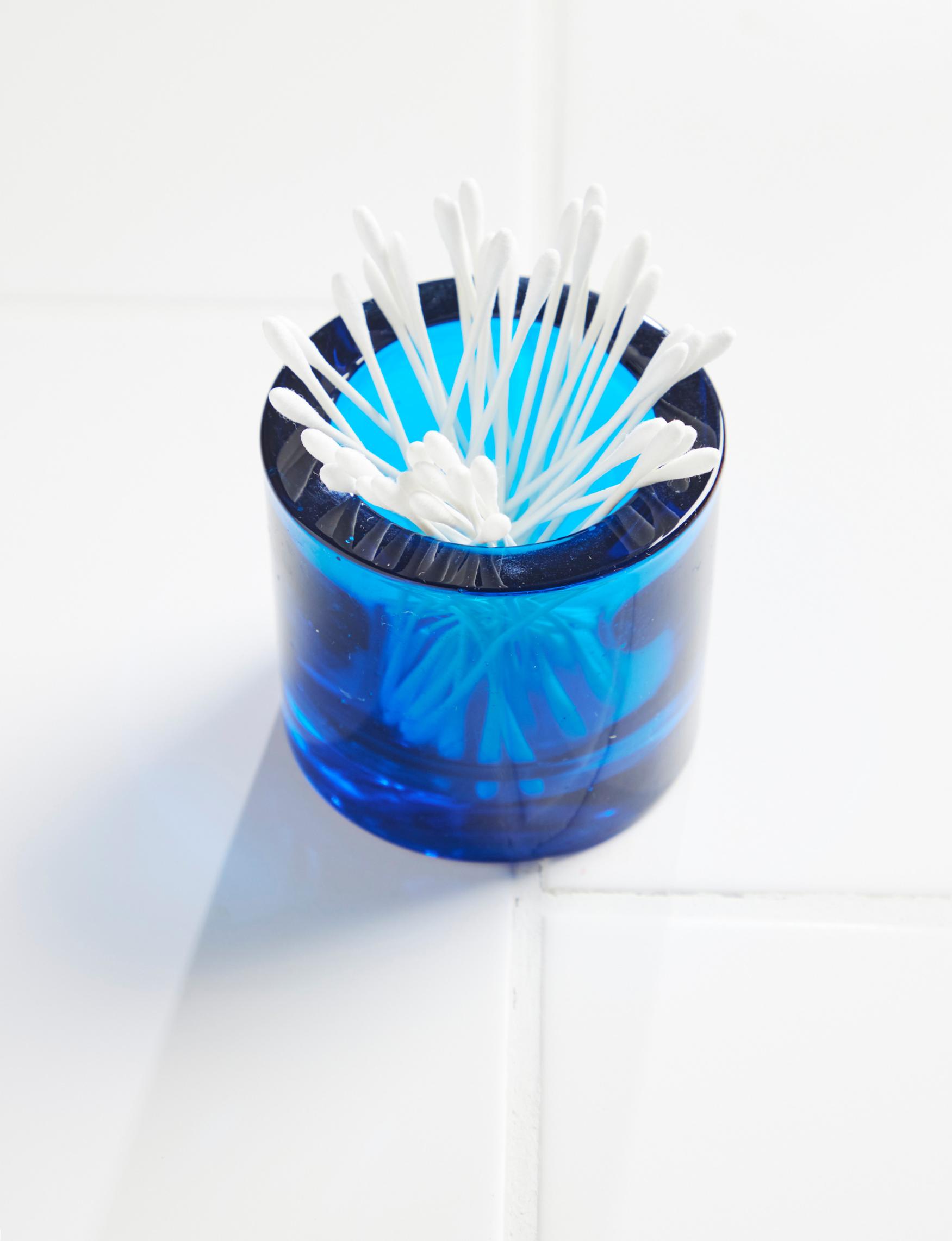 A Kivi tea light holder filled with cotton swabs.
