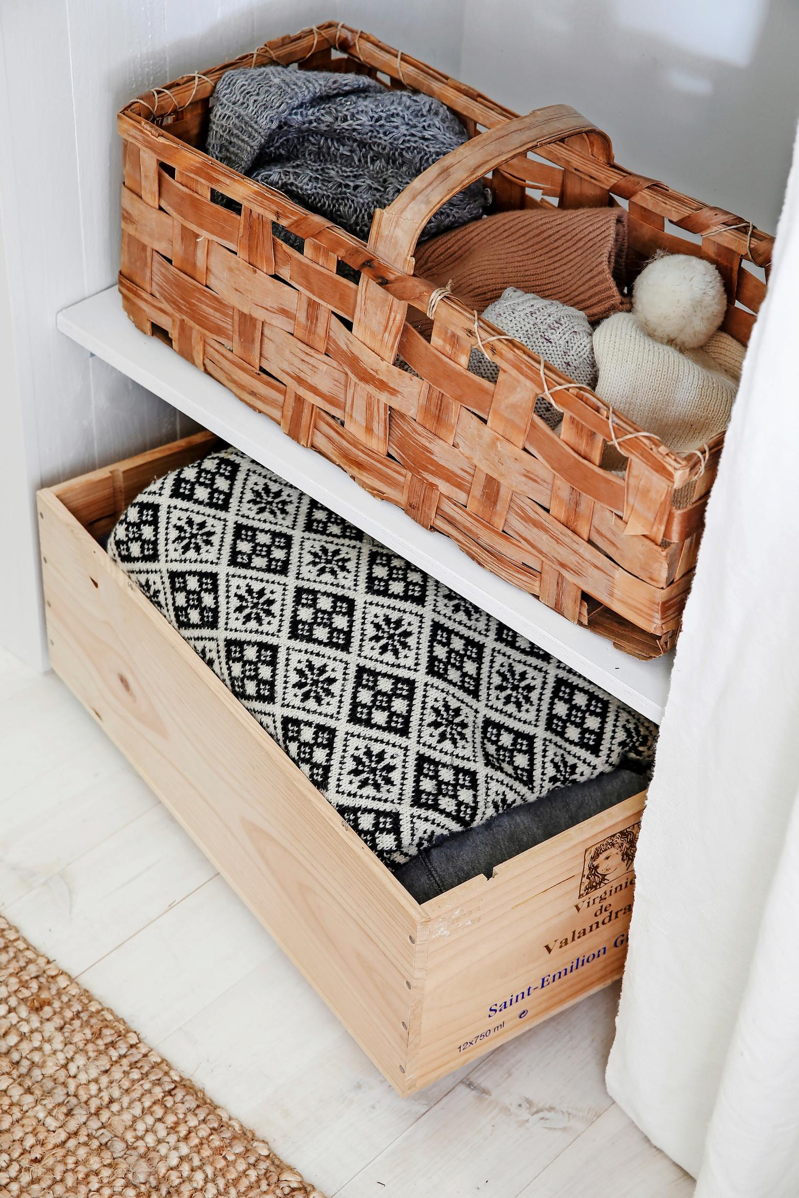 Woven birch baskets and wooden wine boxes on open shelving.