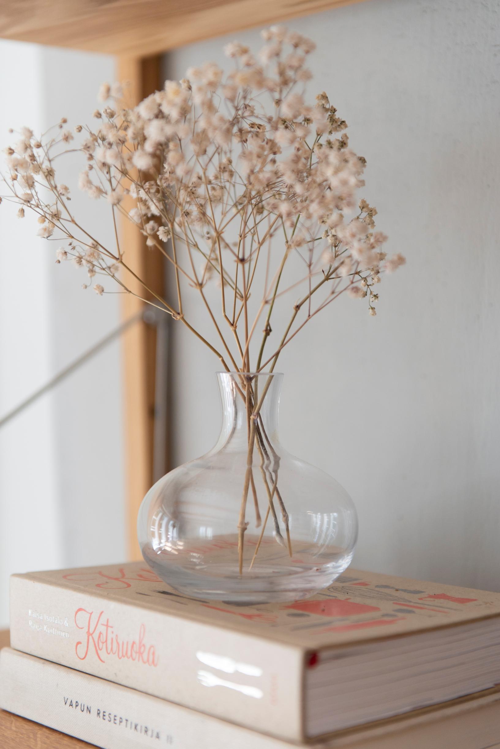 baby’s breath in a glass vase on top of two books