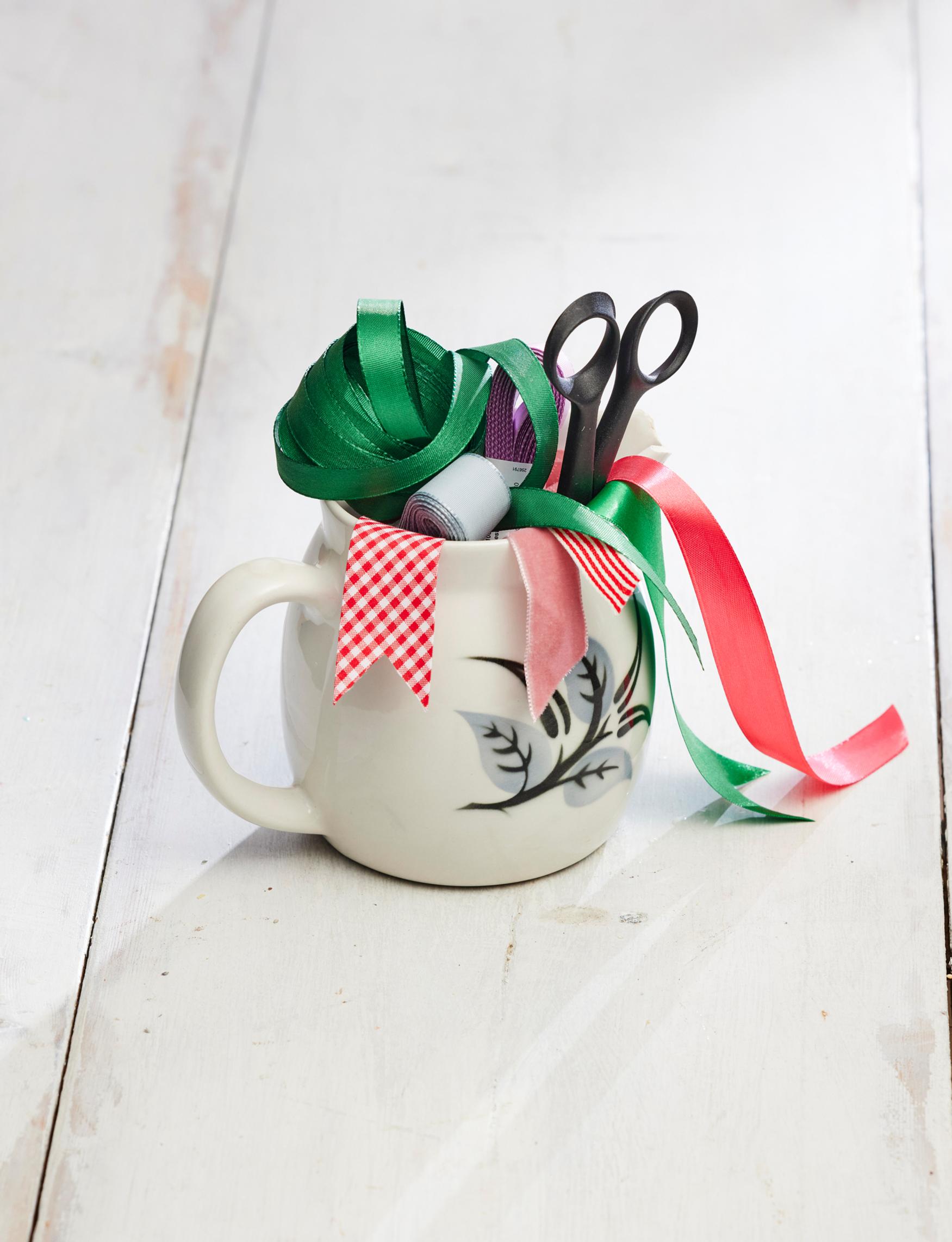 An old Arabia milk pitcher filled with strings and ribbons.