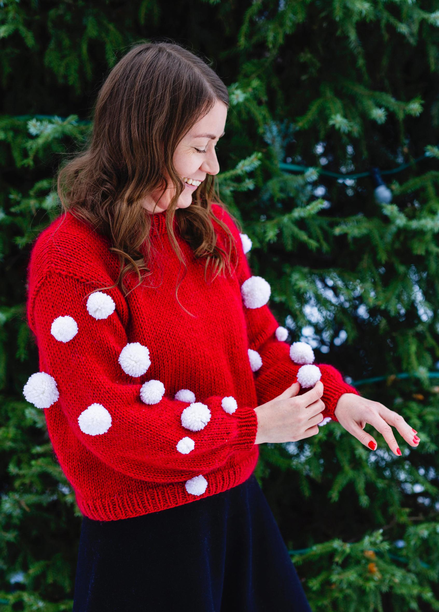 Red Christmas sweater sleeves adorned with pompoms