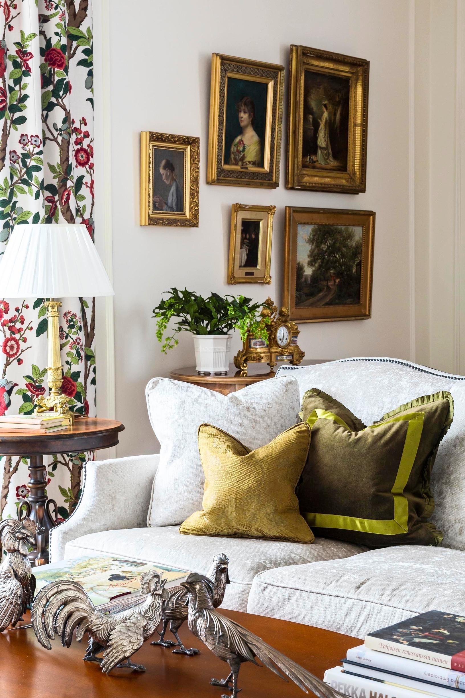 Gold-framed paintings arranged at an angle on the wall behind a sofa