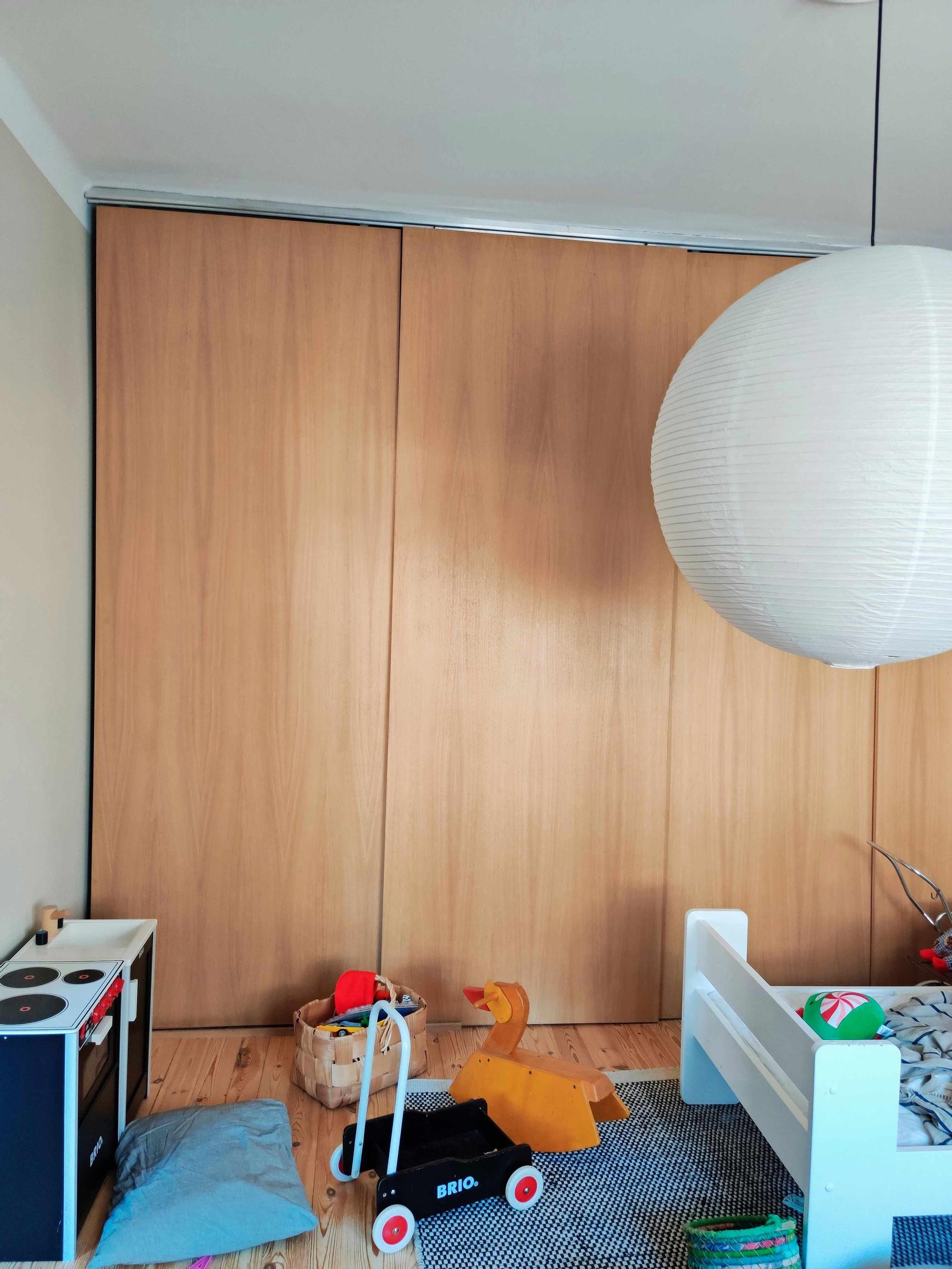 a children’s room with tall wooden doors, a bed, and toys