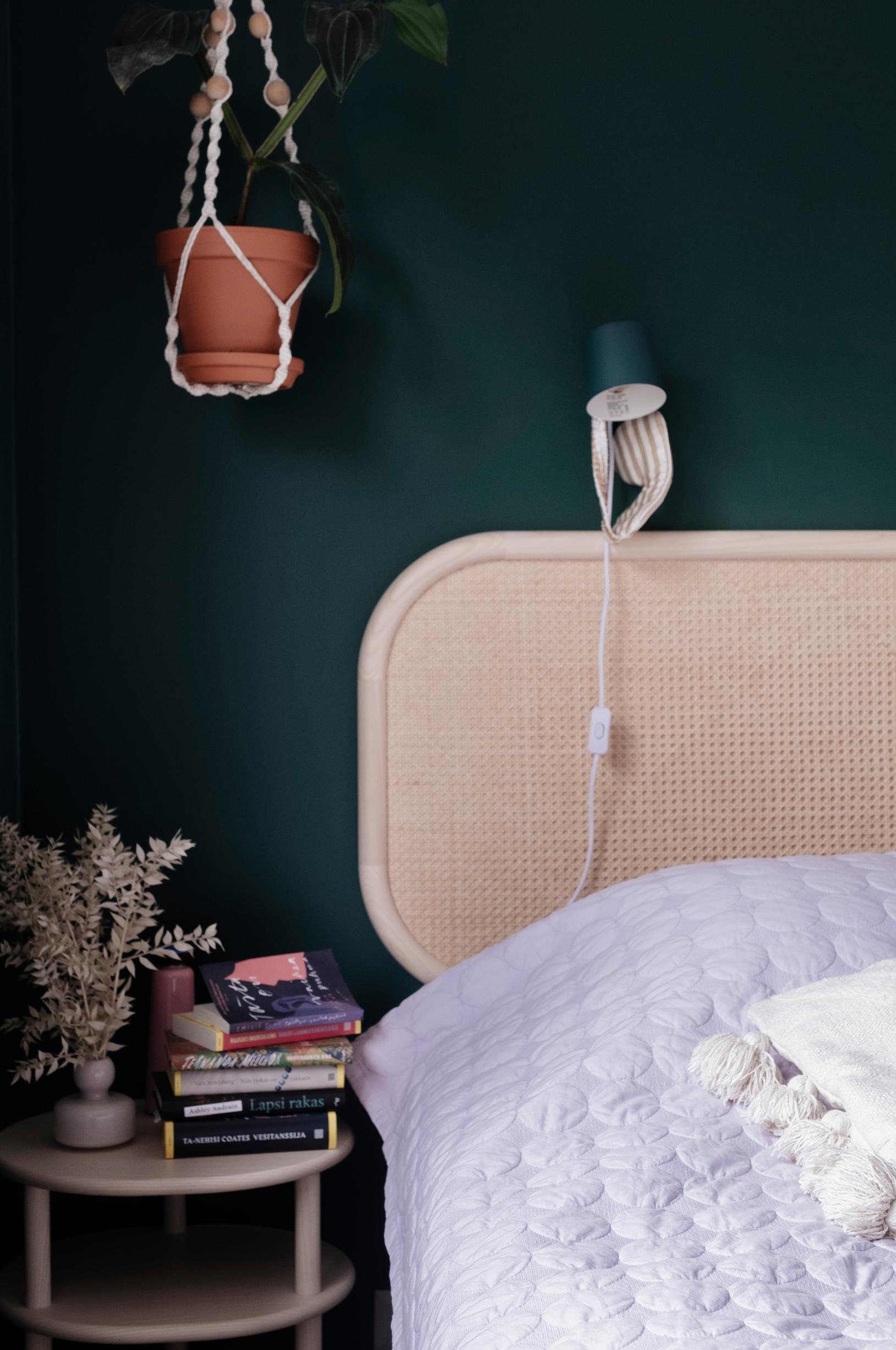 The headboard and nightstands stand out against the dark green walls.