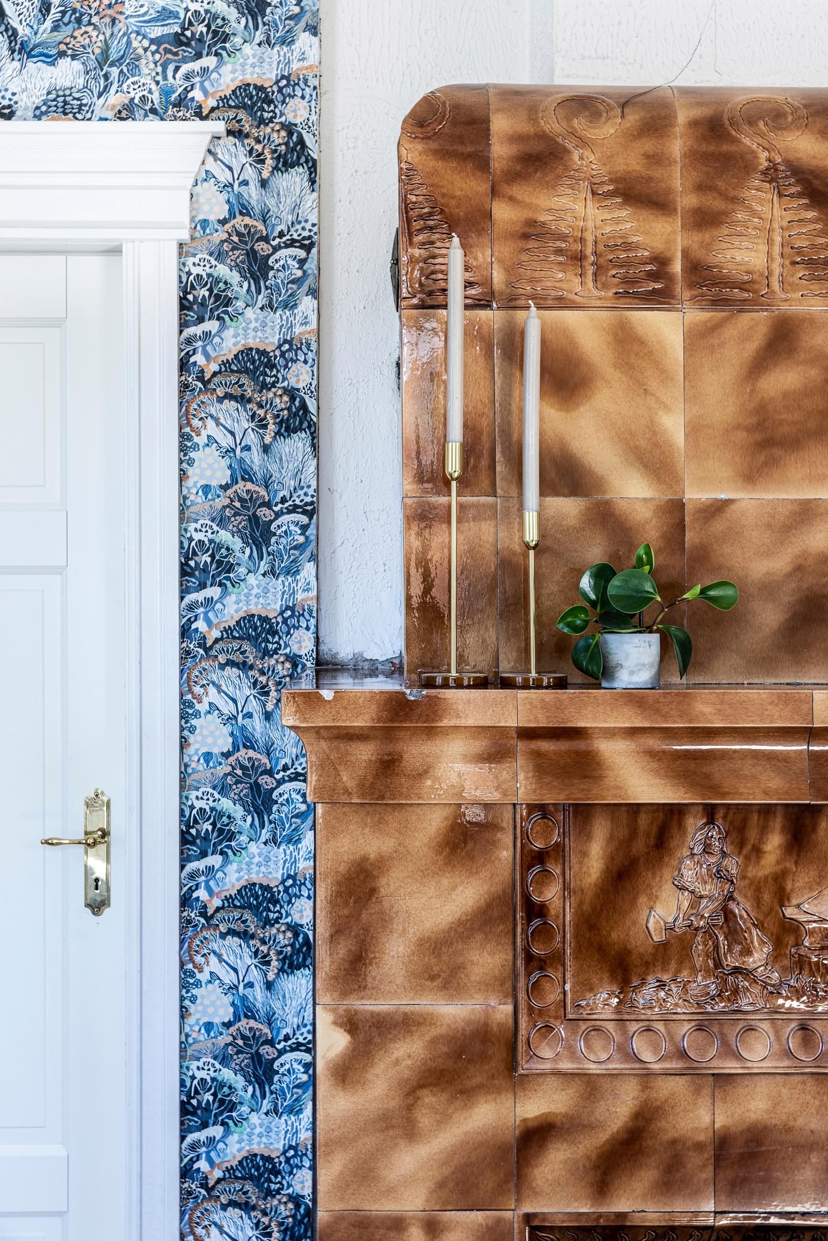brown-toned Seppäuuni, a houseplant, and blue patterned wallpaper