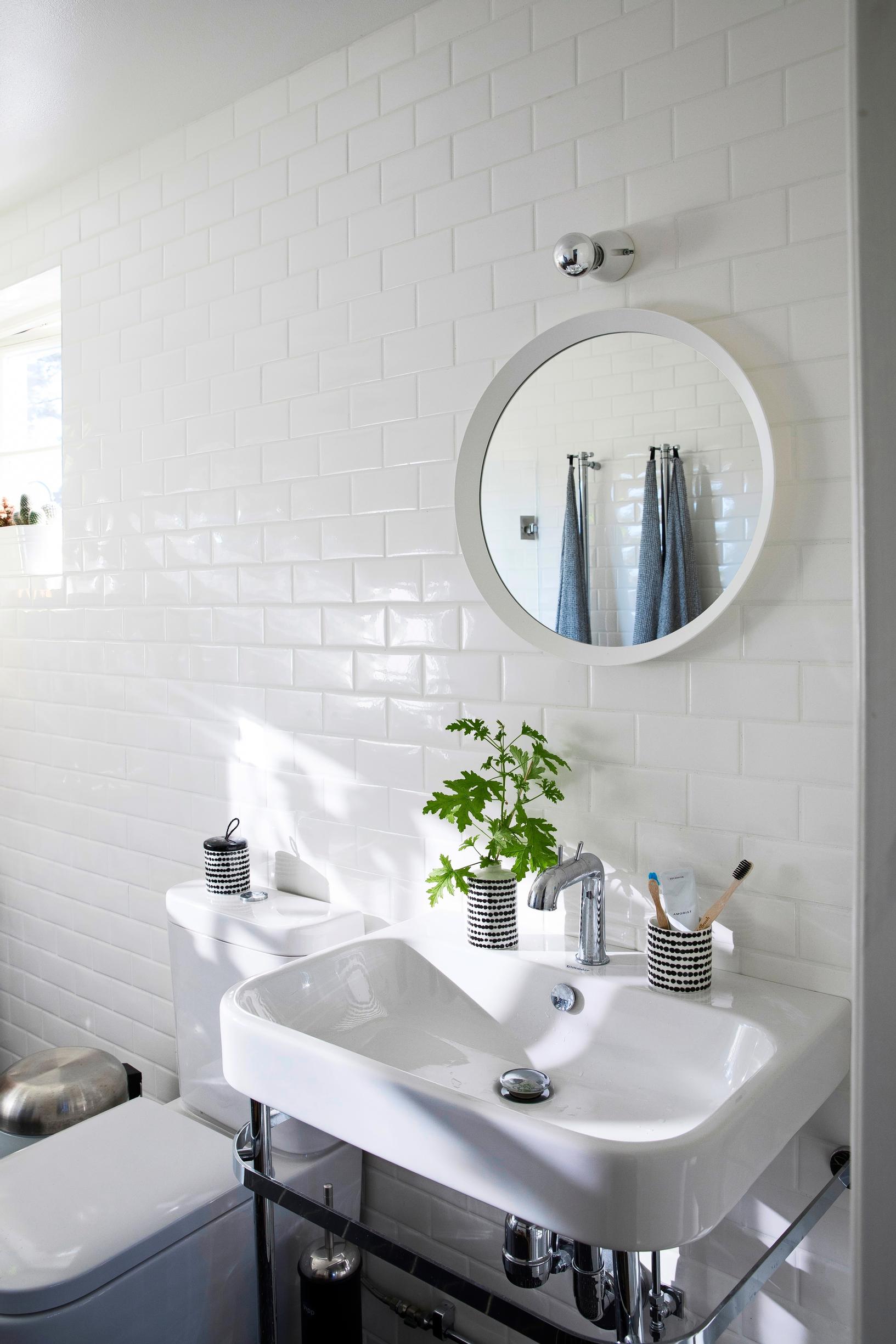 Bright bathroom with classic chrome sink and brick-laid tiles