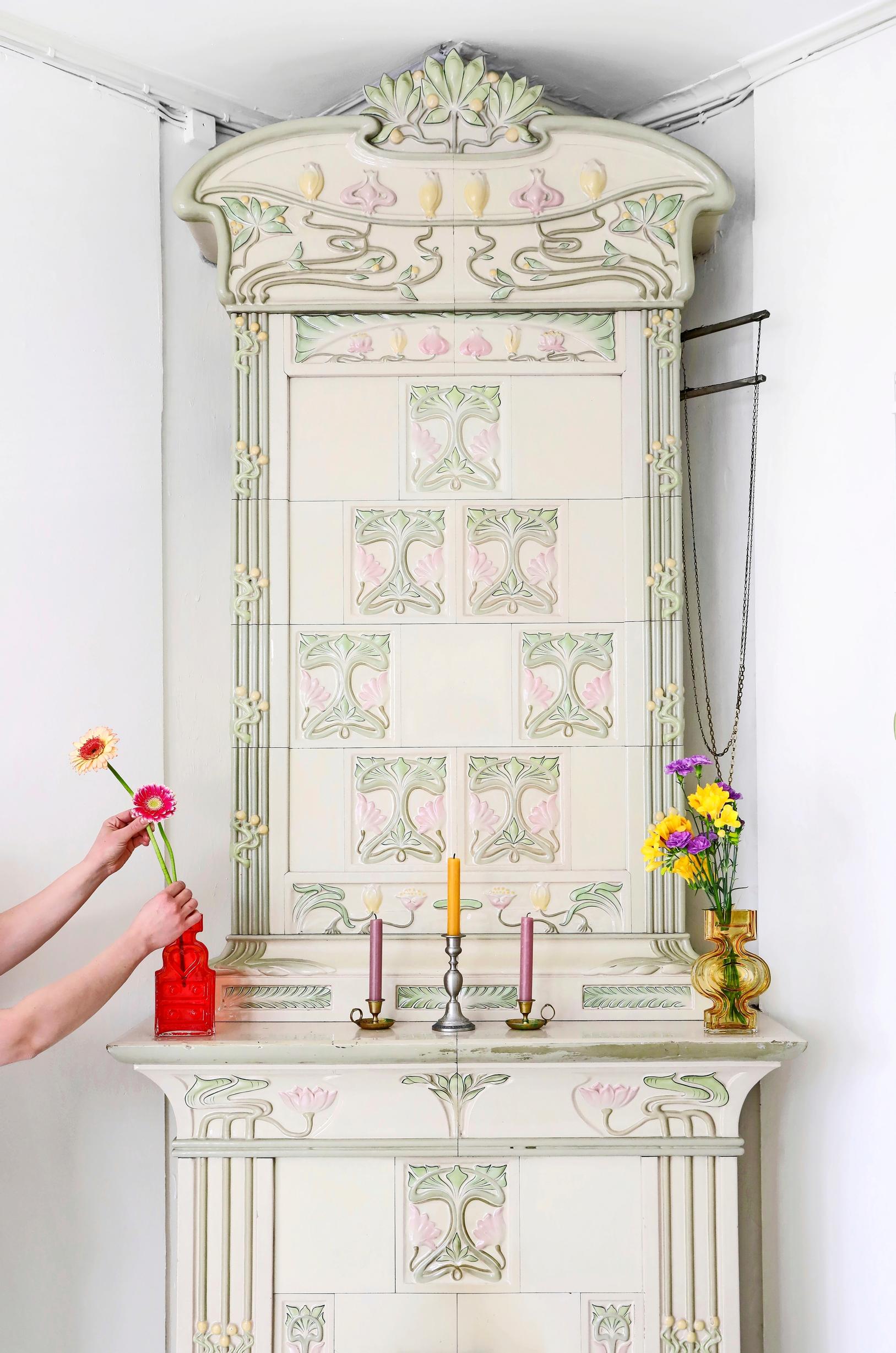 light-toned Turun Kaakelitehdas Lumpeenkukkauuni and a pair of hands arranging flowers in a vase