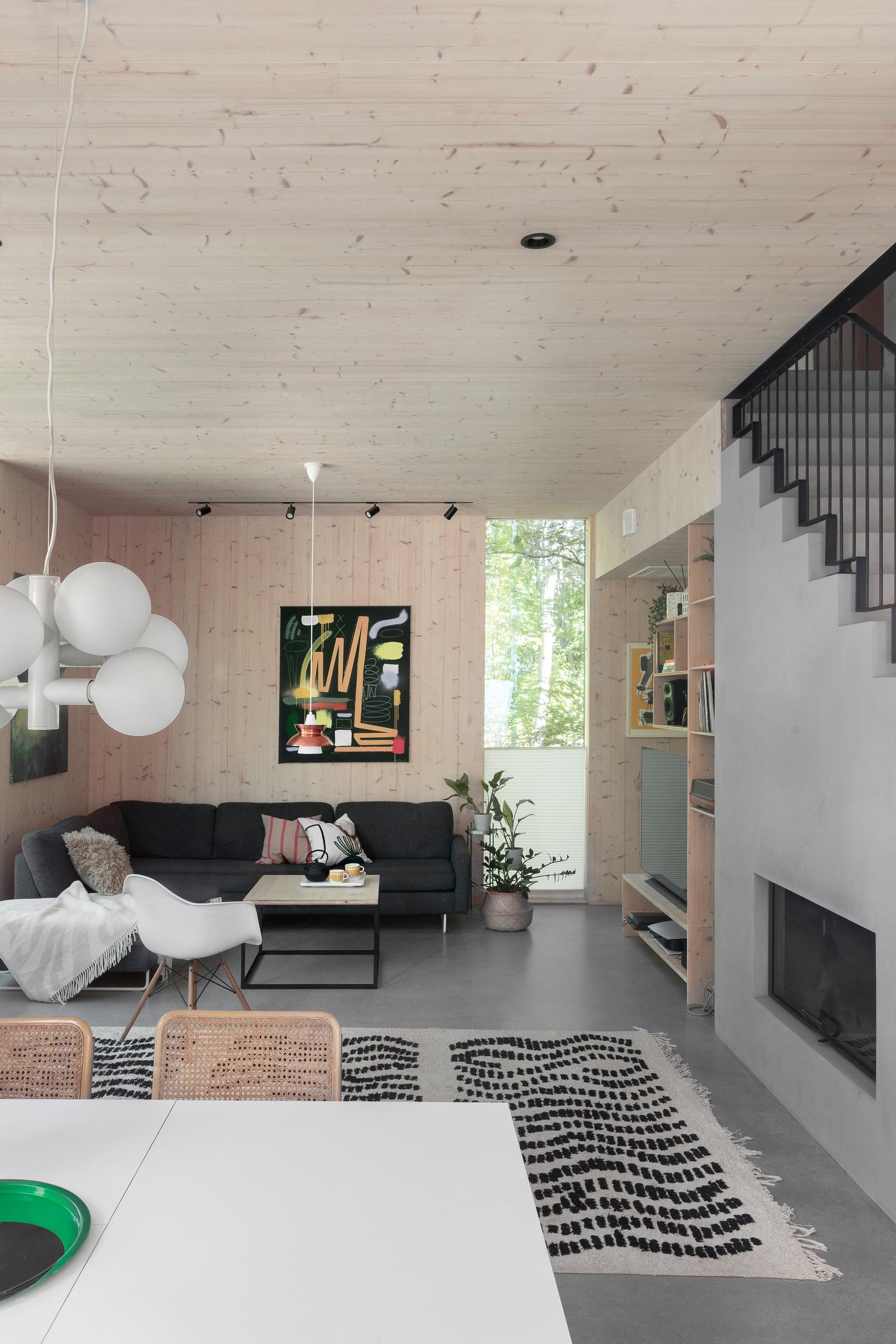 In the CLT home's living room, there are wood-paneled walls, a sofa, and a fireplace beneath the stairs.