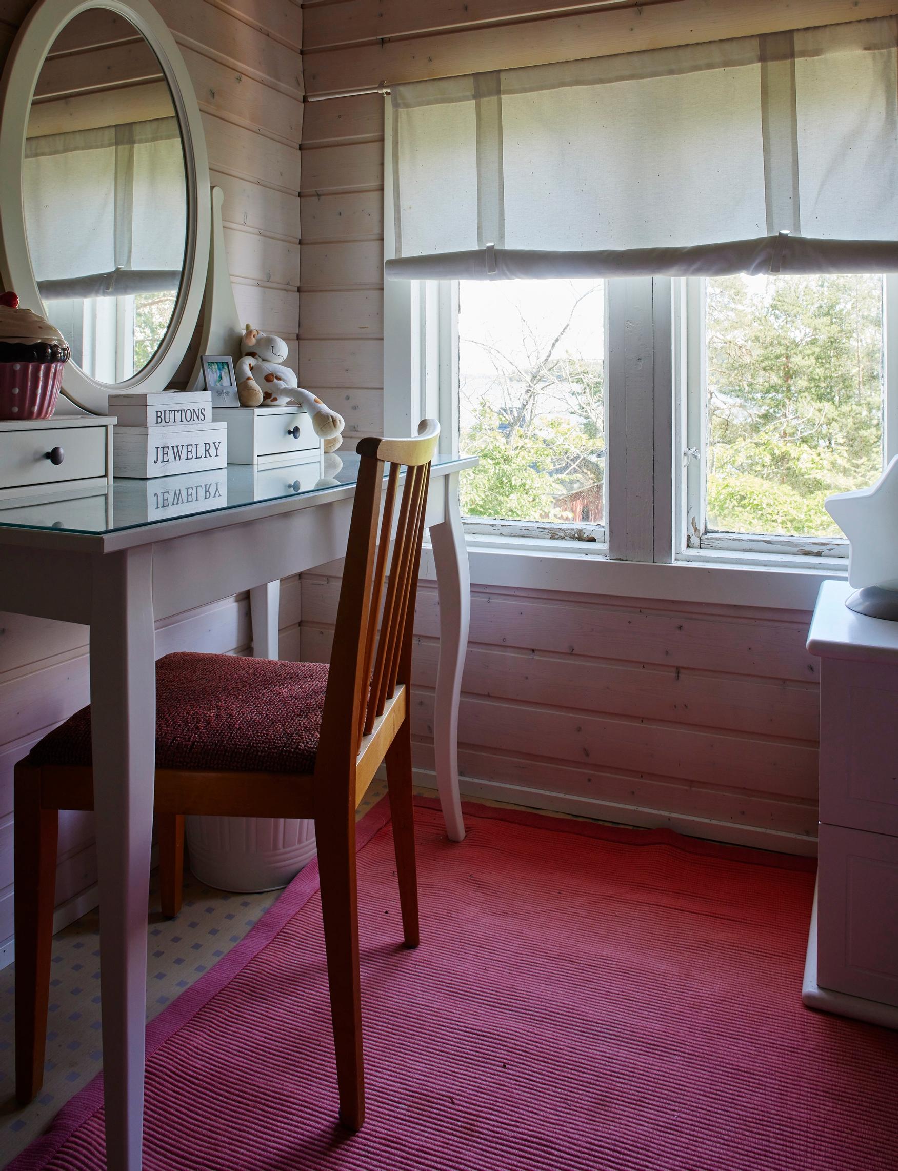 a red rug, white table and wooden chair by a window