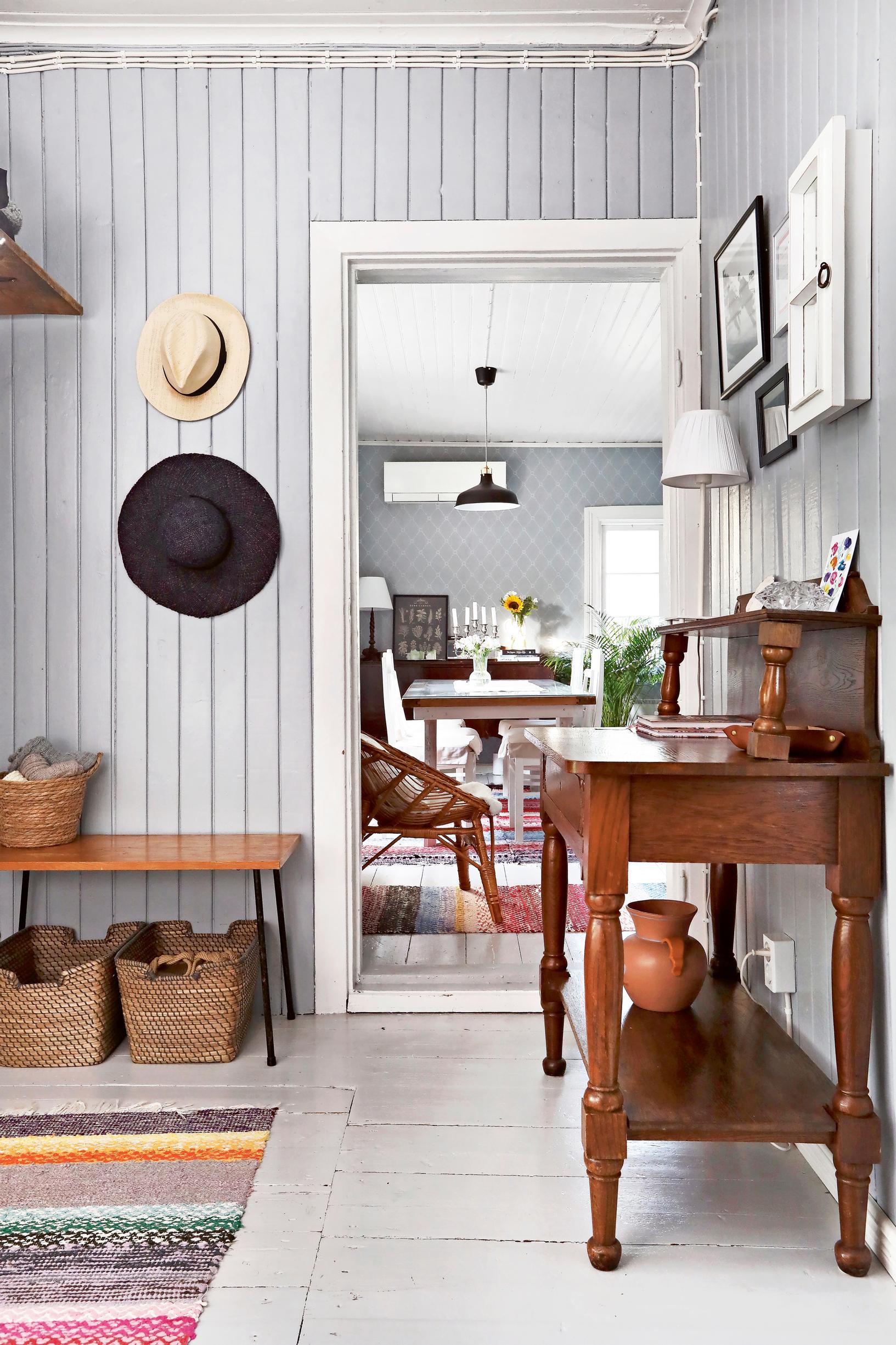 Hallway side table, bench, baskets, hats on the wall, and rag rug