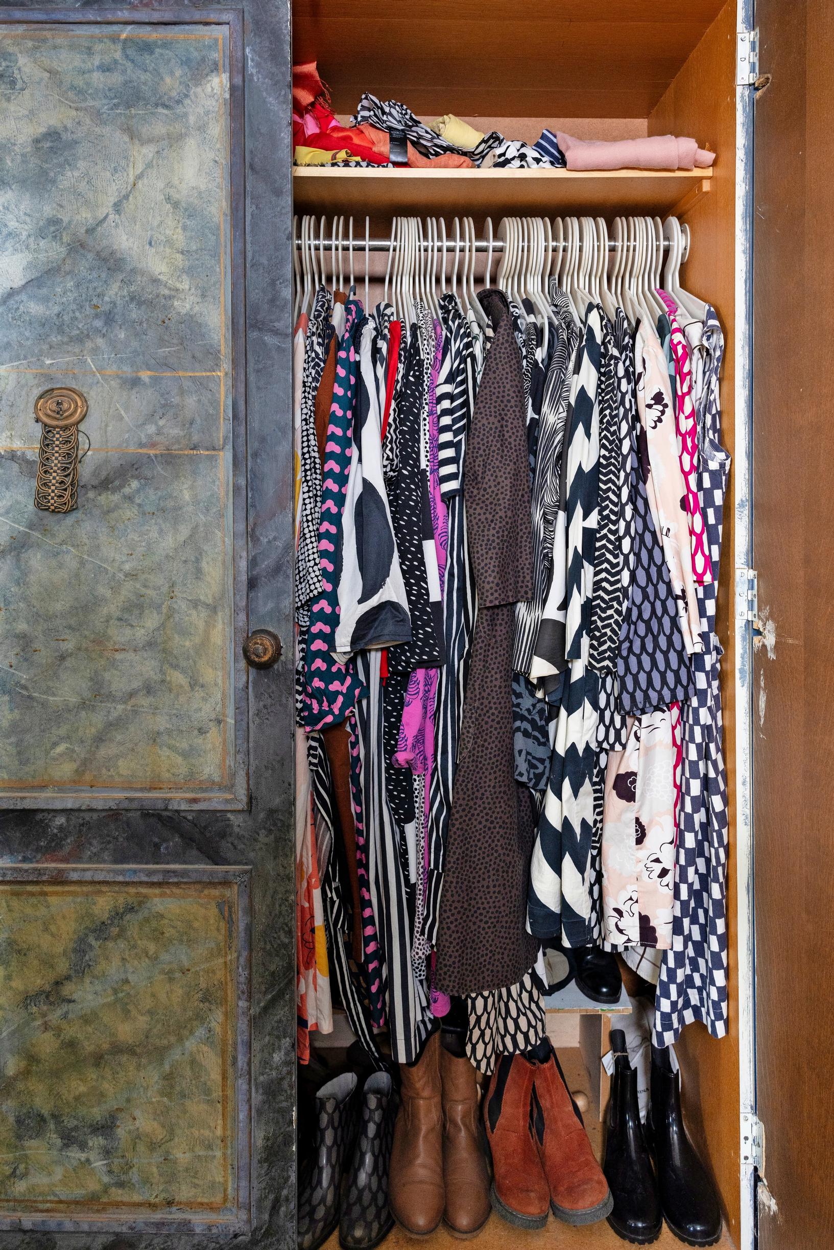 One wardrobe door is open, revealing old Marimekko garments inside.
