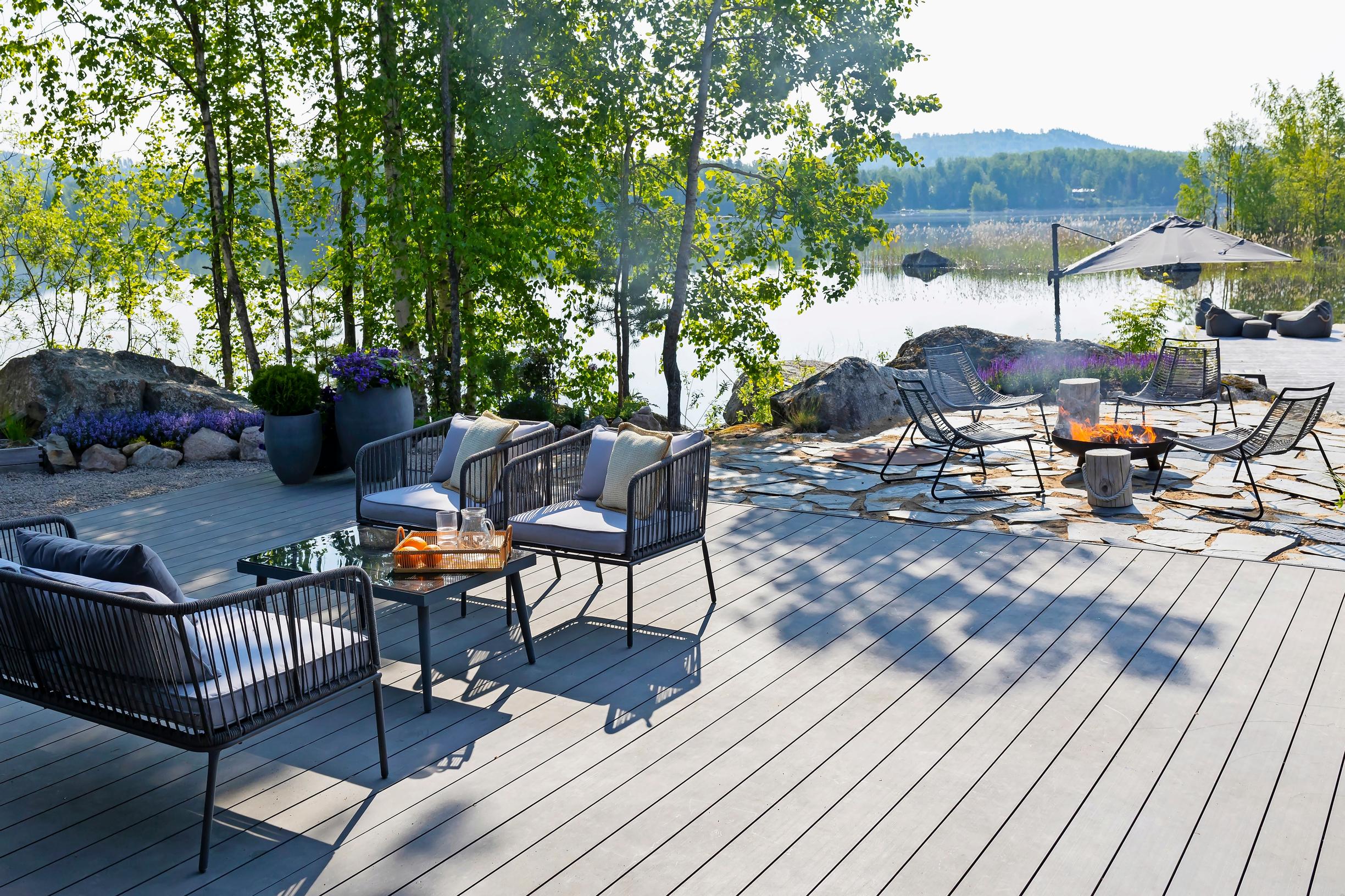 a dining set and a fire feature on the cabin terrace, with trees and the lake in the background