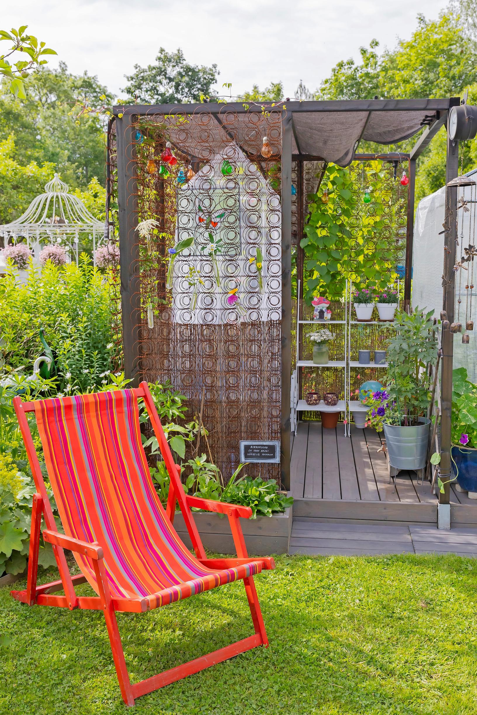 a red deck chair on the lawn in front of the garden canopy