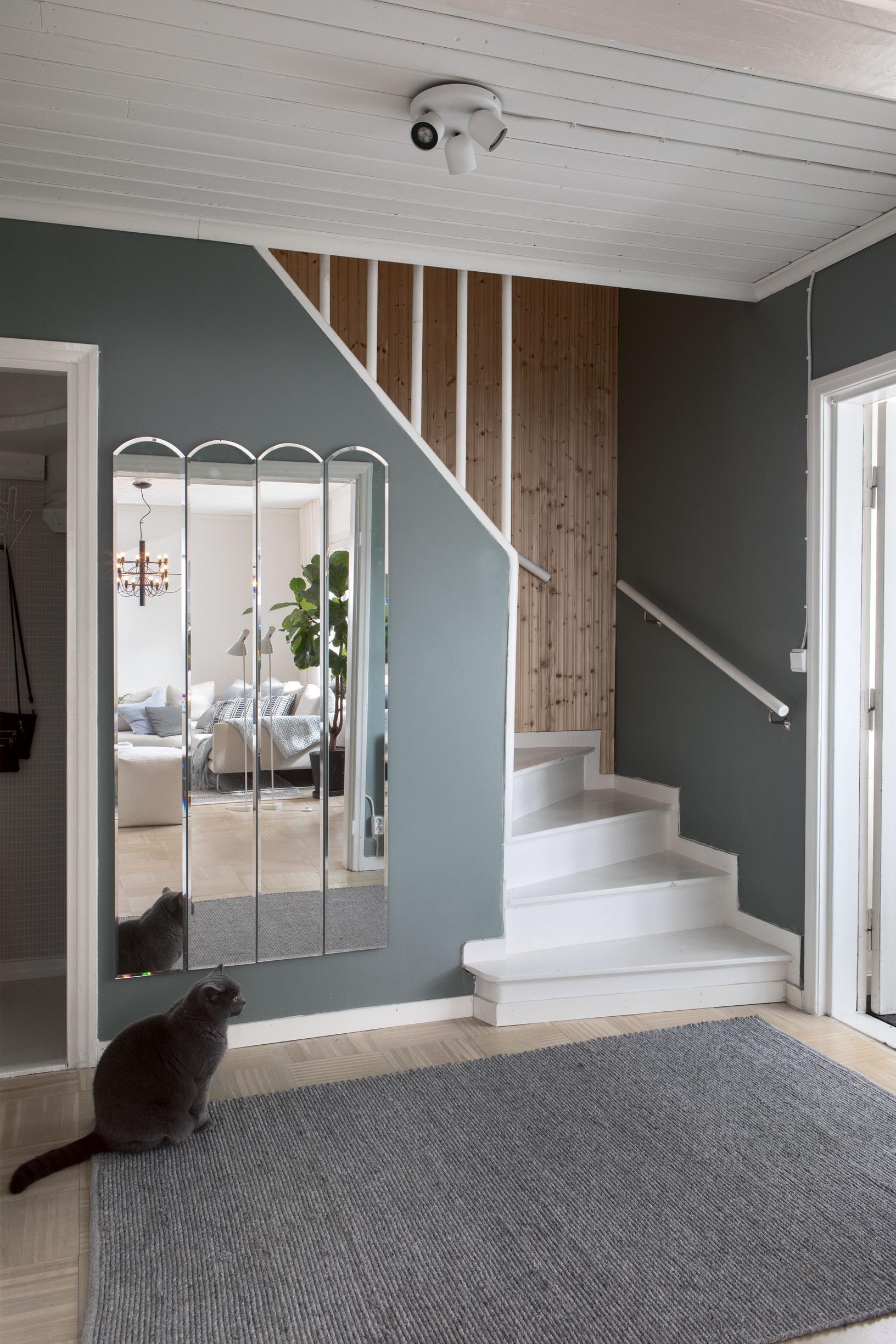 In the entryway, stairs lead upstairs, and a large mirror hangs on the wall.