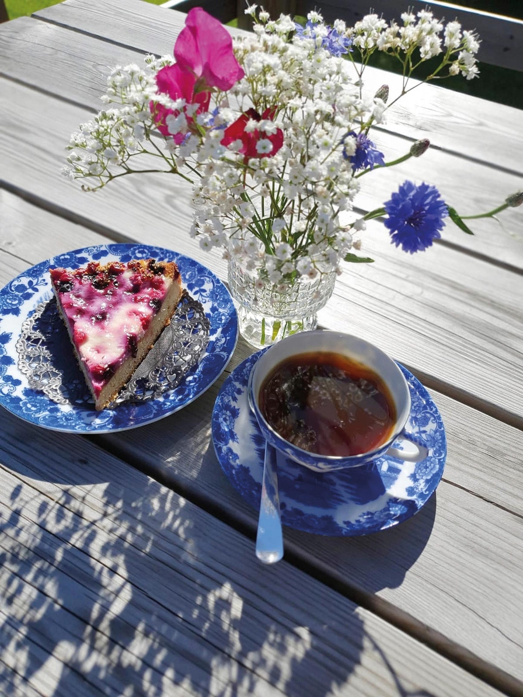Coffee cup and some blueberry pie on a saucer on an outdoor terrace