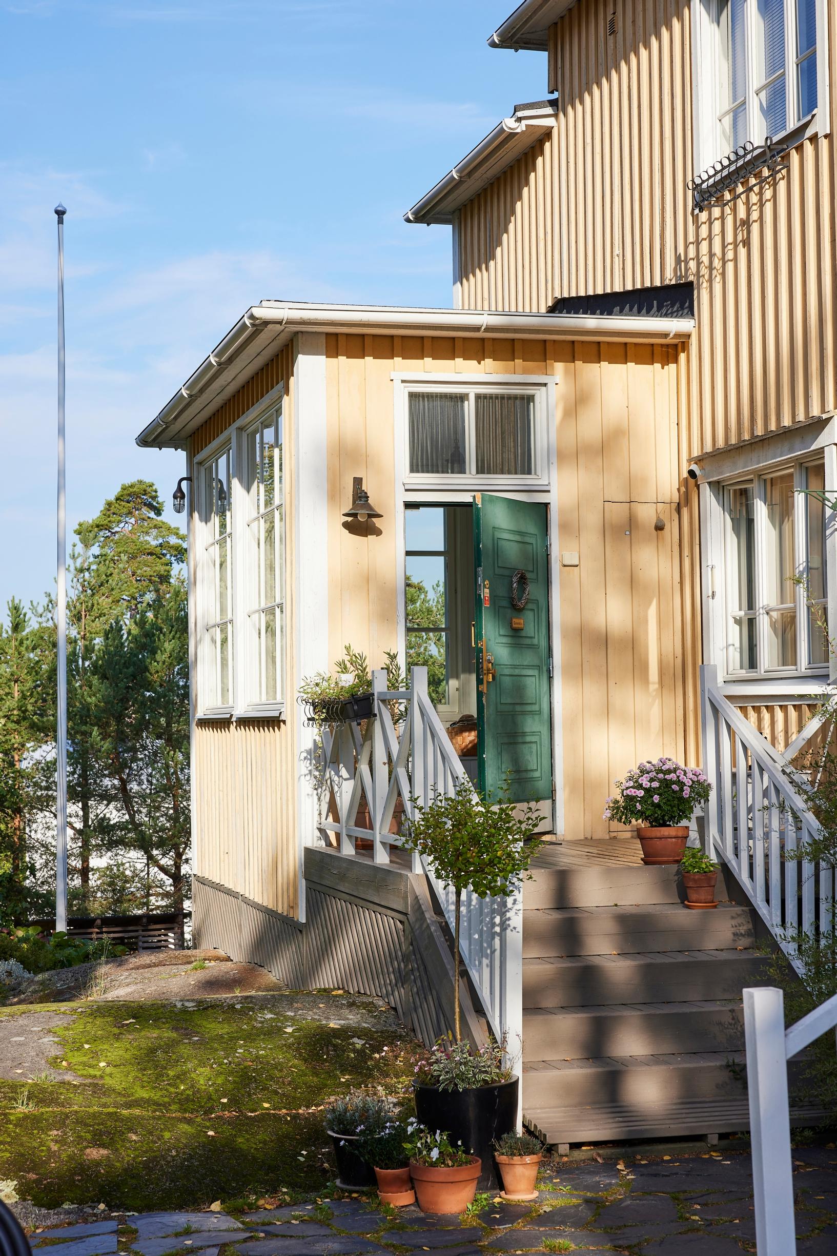 Entrance to the wooden house with a green door