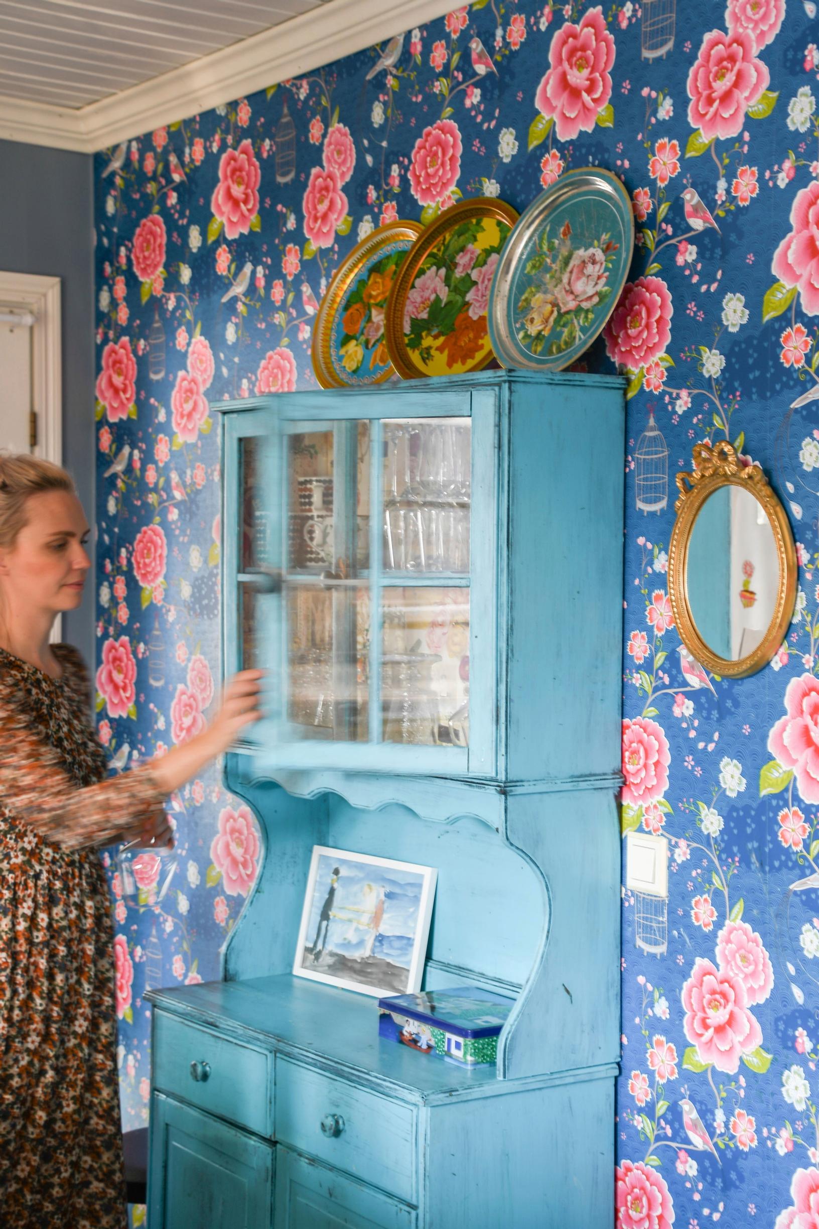 Colorful wallpaper and a blue dish cabinet.