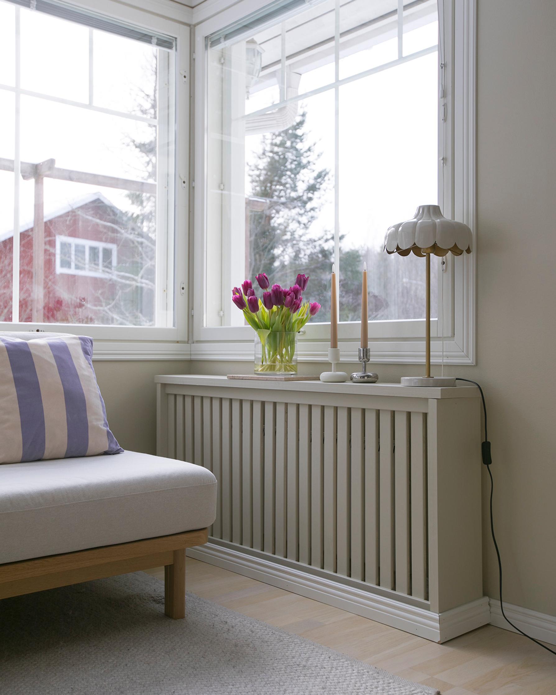 A living room featuring a wooden-framed sofa and a wooden enclosure around the radiator
