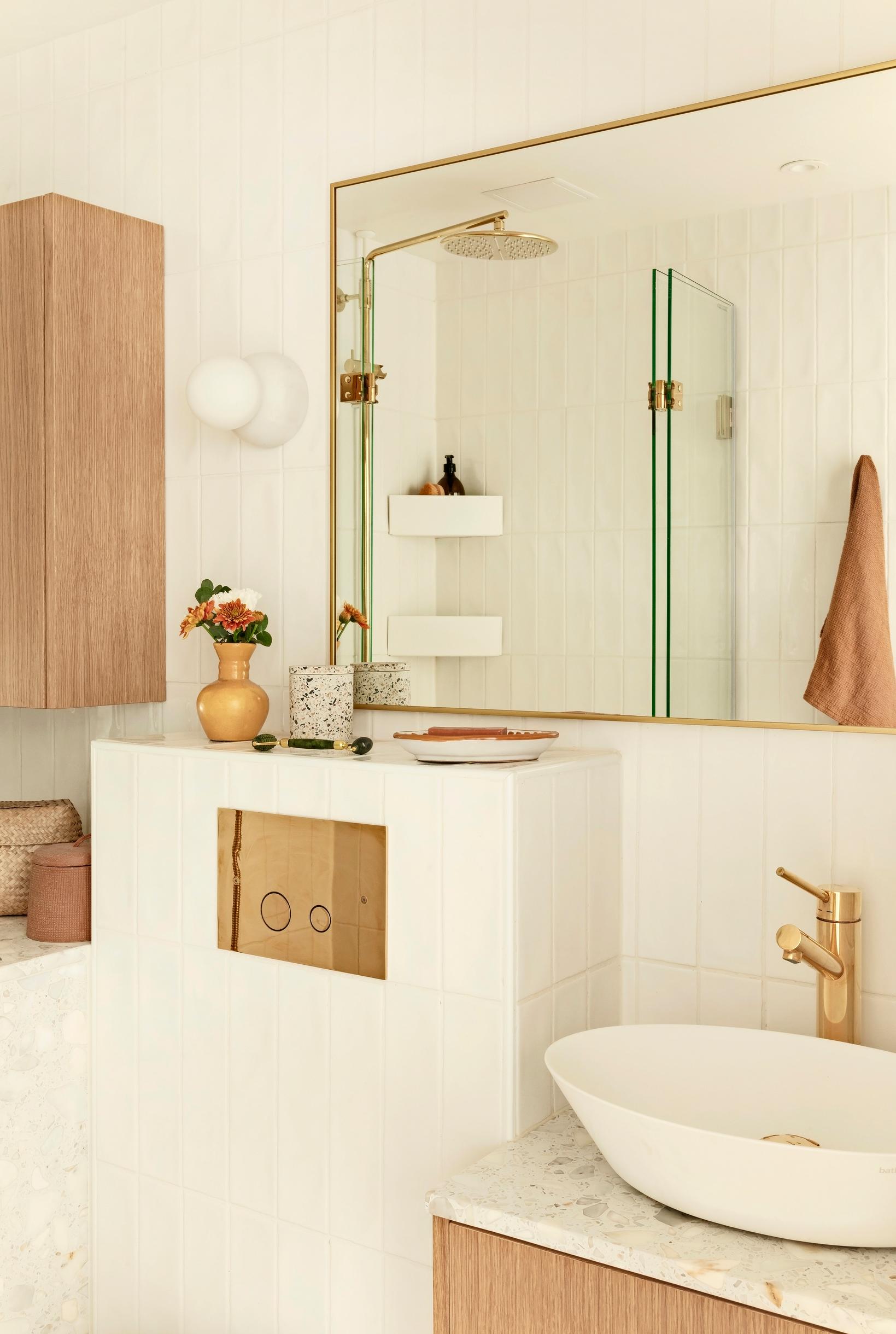 A large mirror, oak veneer cabinets, and gold accents in the bathroom