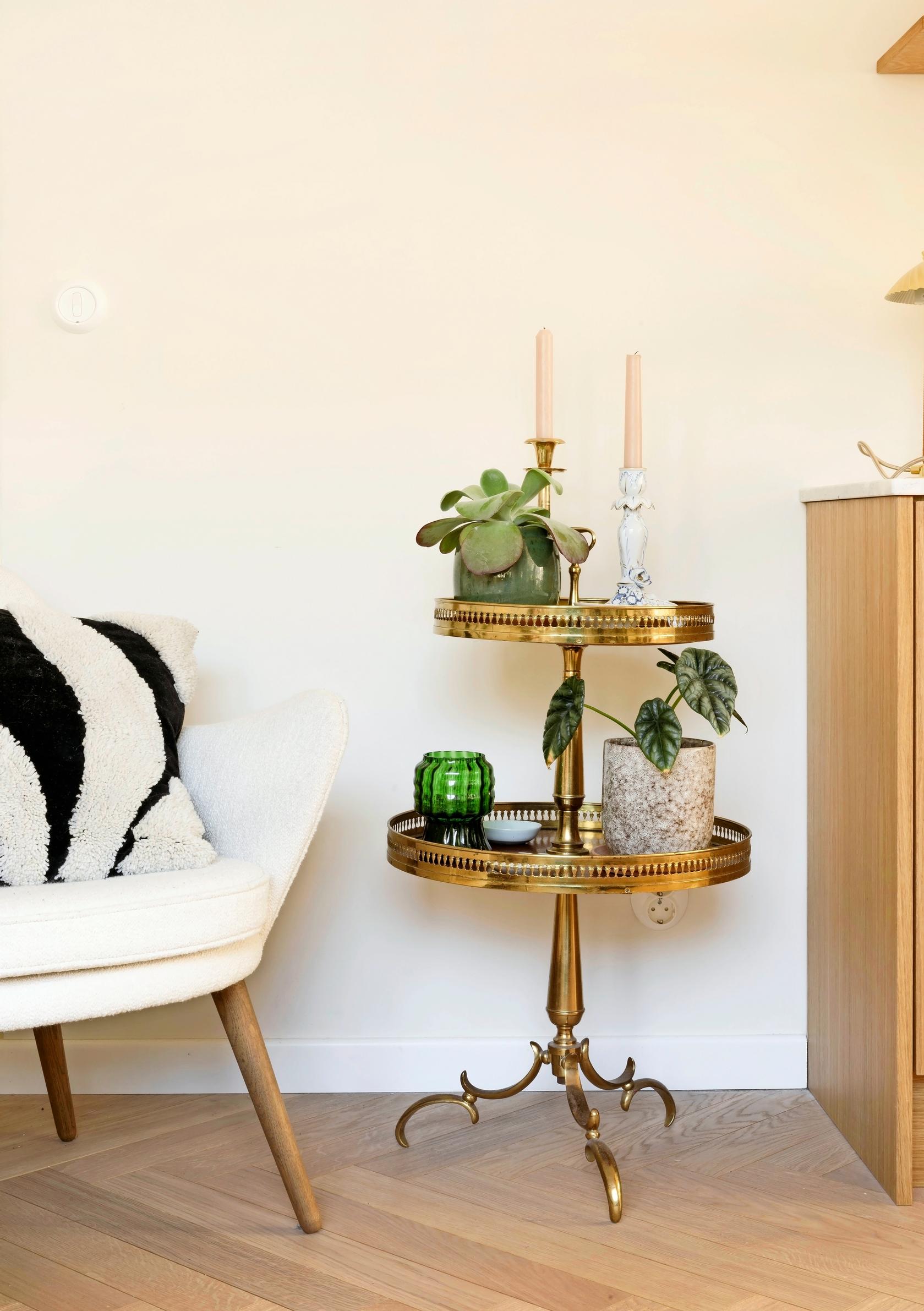 Two-tier brass table and a white armchair.