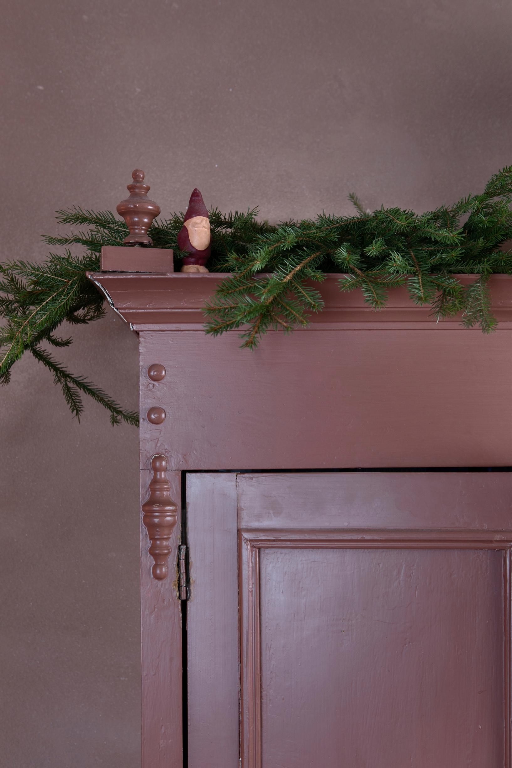 Wooden cabinet in rosy pink and an evergreen garland