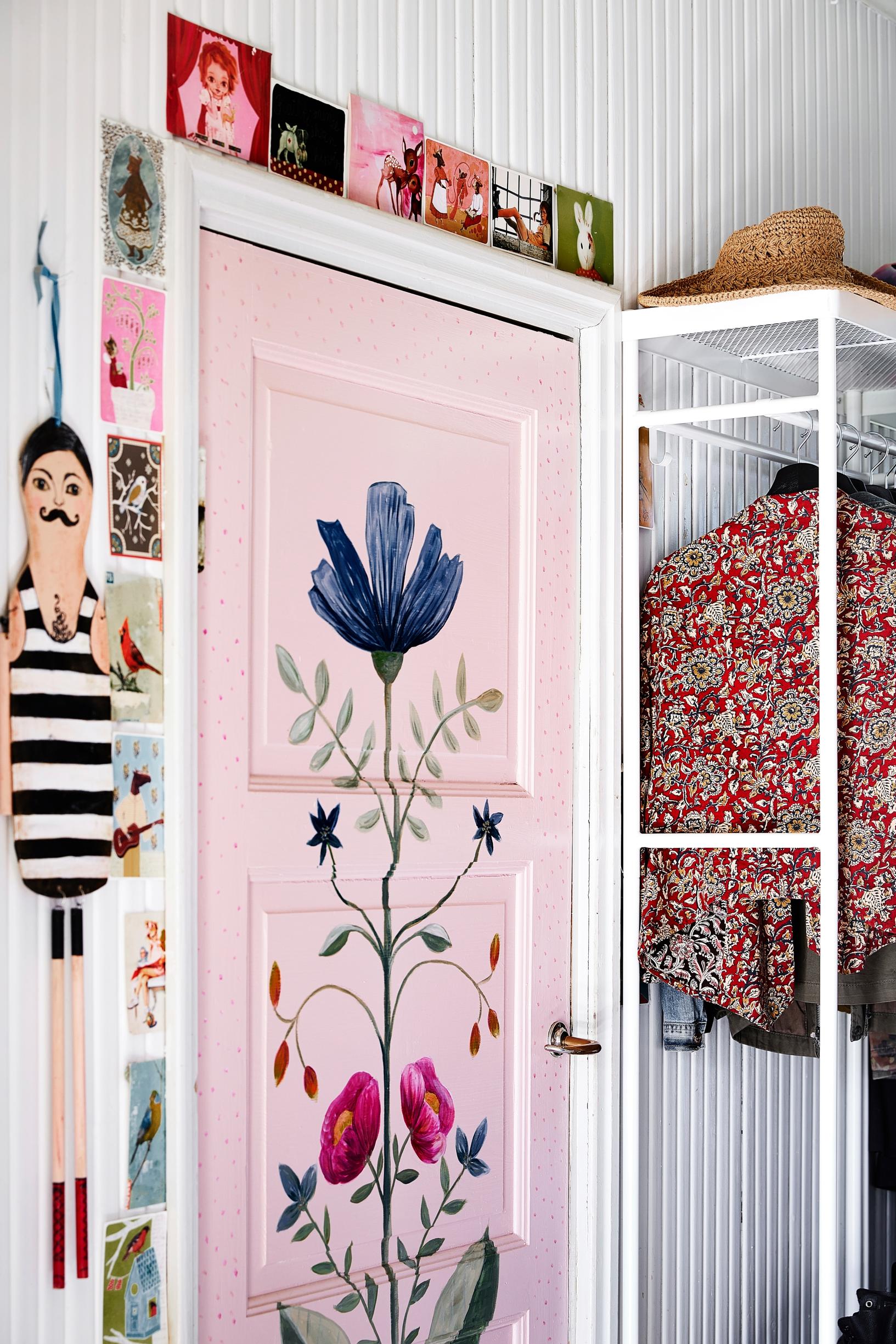 A pale pink door with a lovely floral painting.