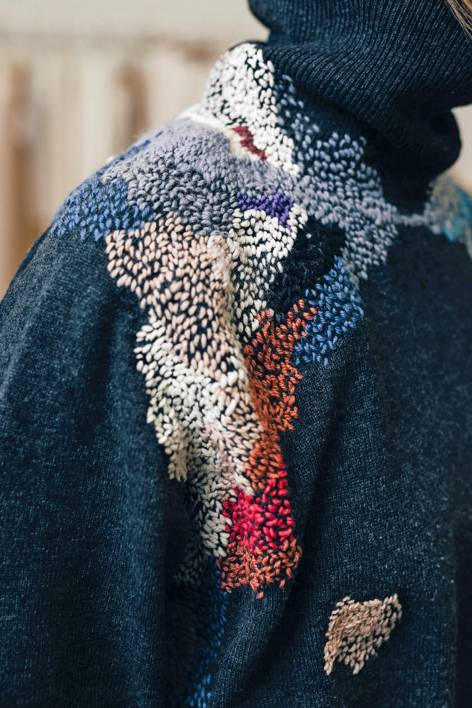 Minna wearing a sweater with extensively mended and embroidered shoulders.