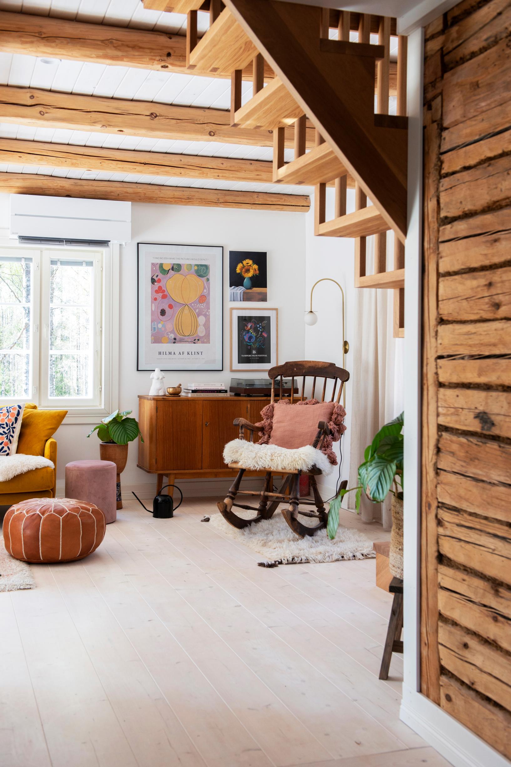 Rocking chair, sideboard, and paintings under exposed ceiling beams
