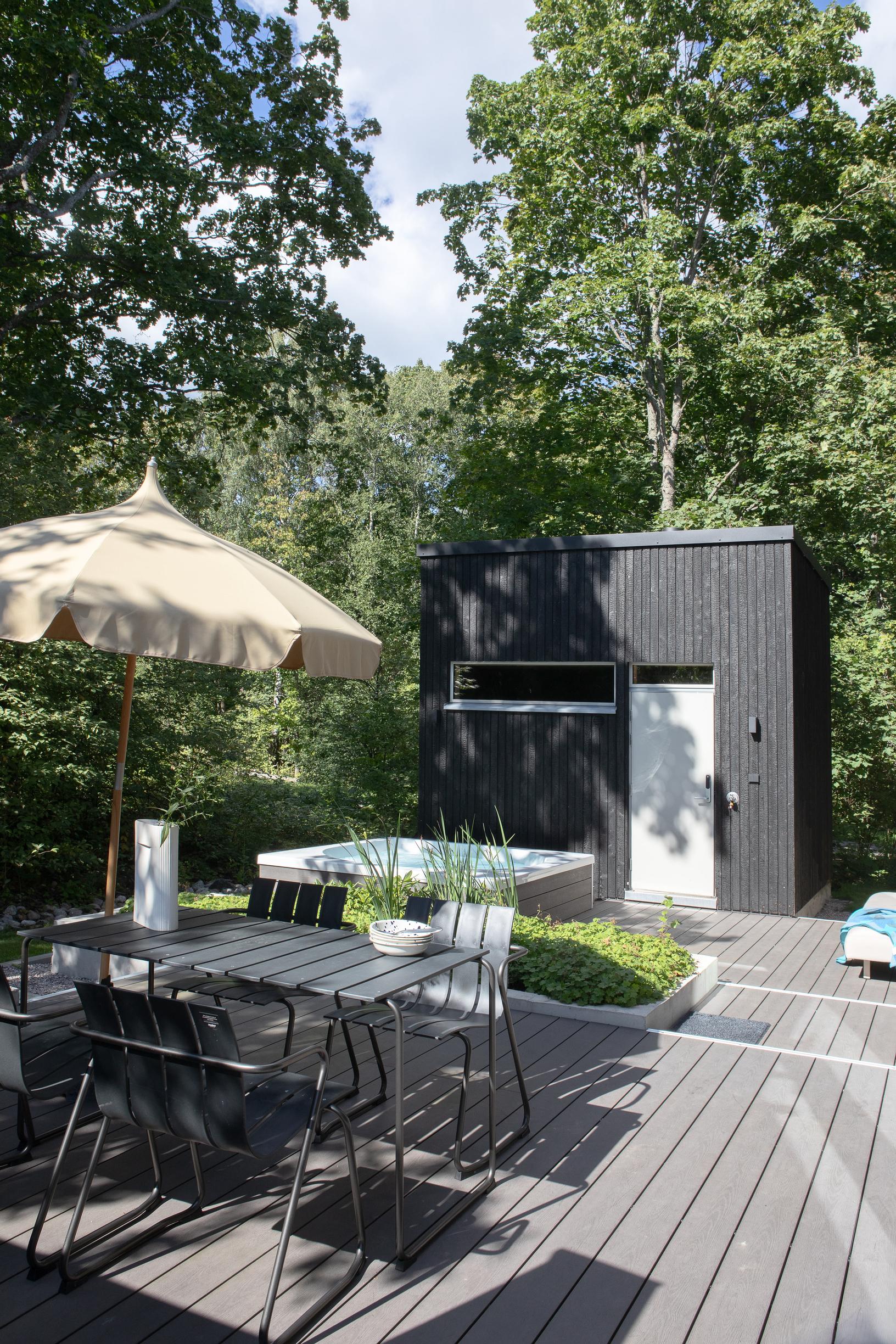 On the two-level deck, there’s an outdoor dining suite and a hot tub. The backyard sauna stands behind the terrace.