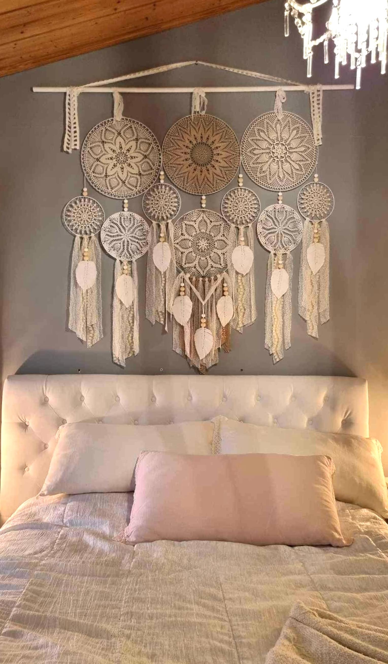 Above the headboard, there's a piece made of multiple stretched lace doilies.
