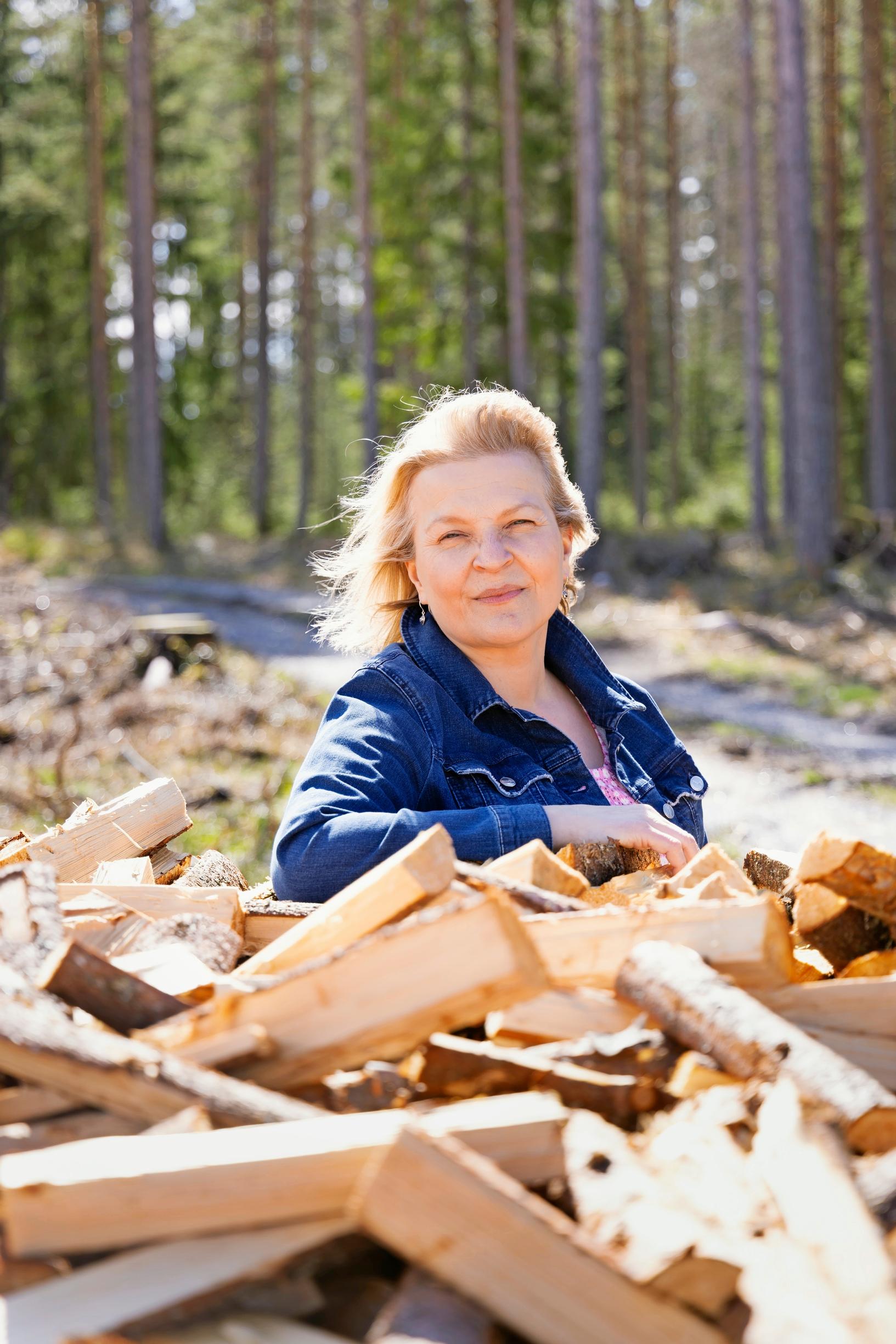Author Anu Joenpolvi and a stack of firewood in their home yard