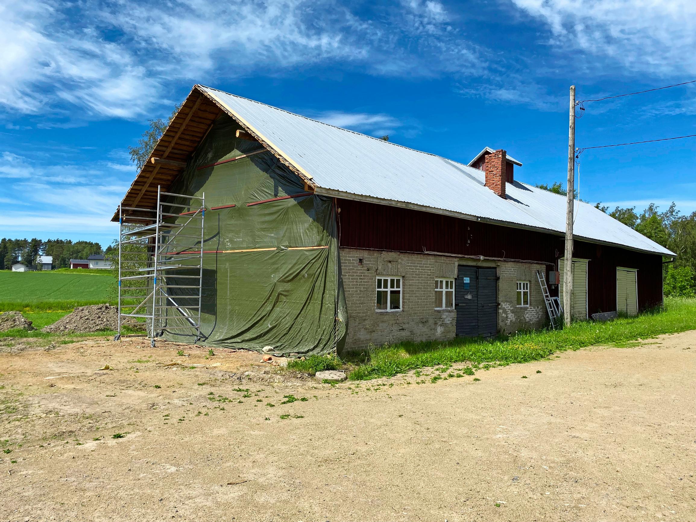 The cow barn wall after the extension has been removed. The wall is protected with a tarp.