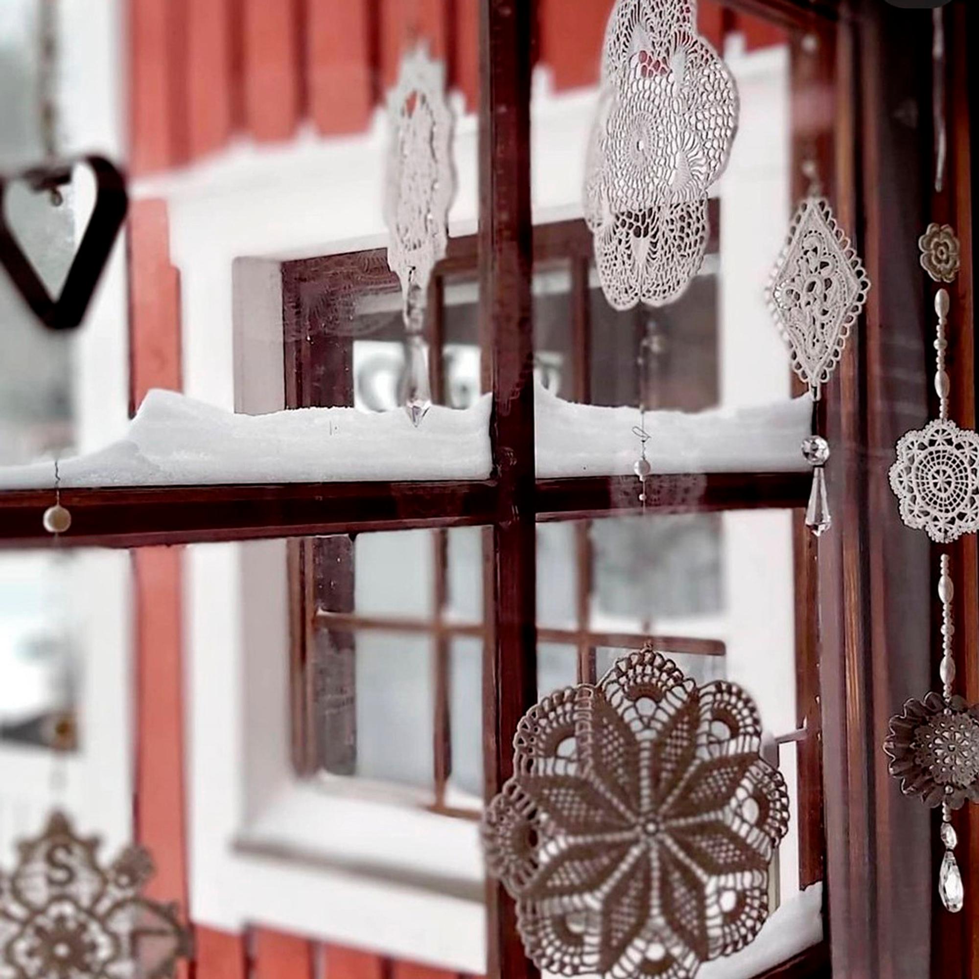 Hanging lace doilies at the window, looking like snowflakes.