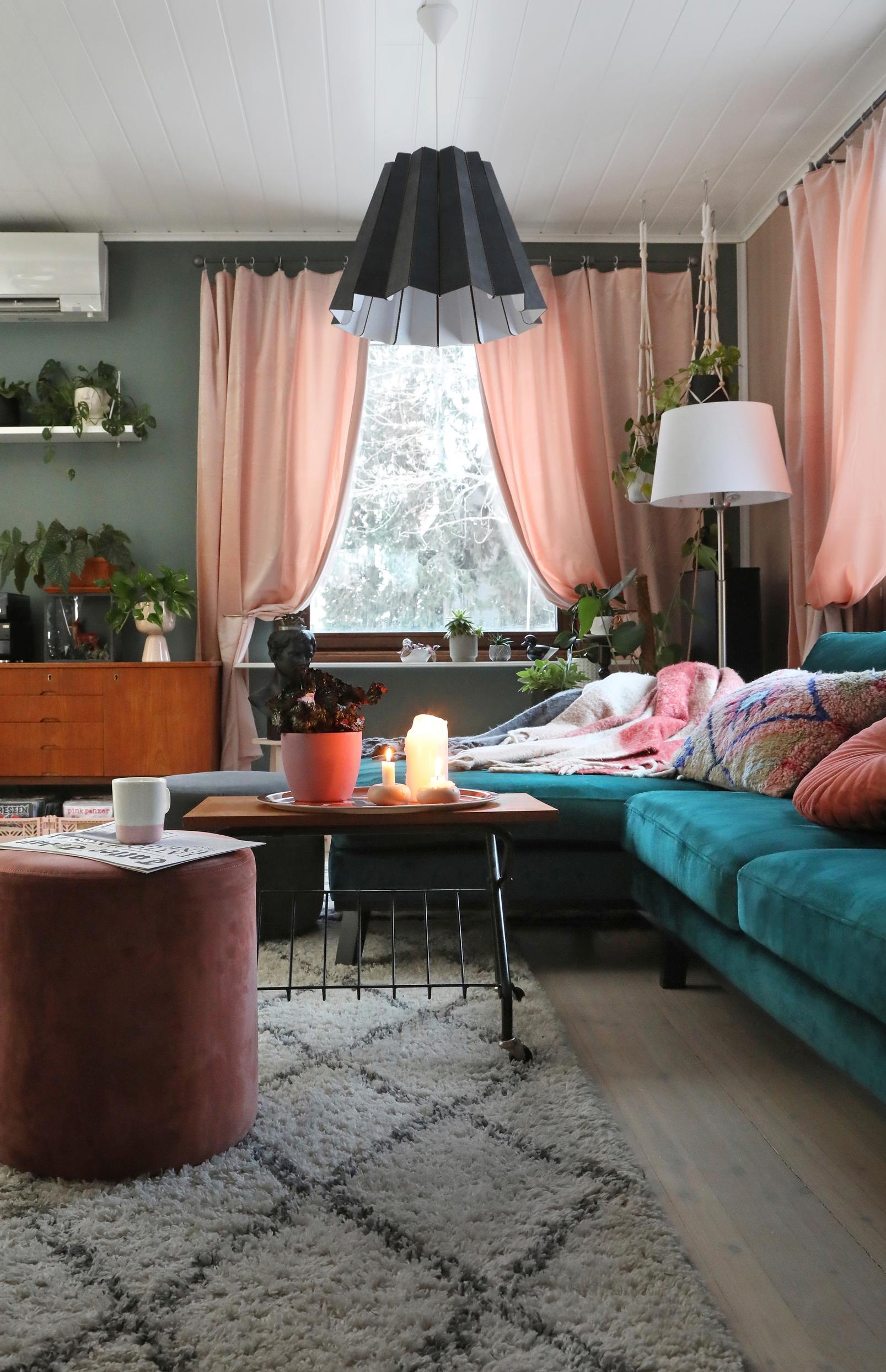 A turquoise velvet sofa and pink window curtains