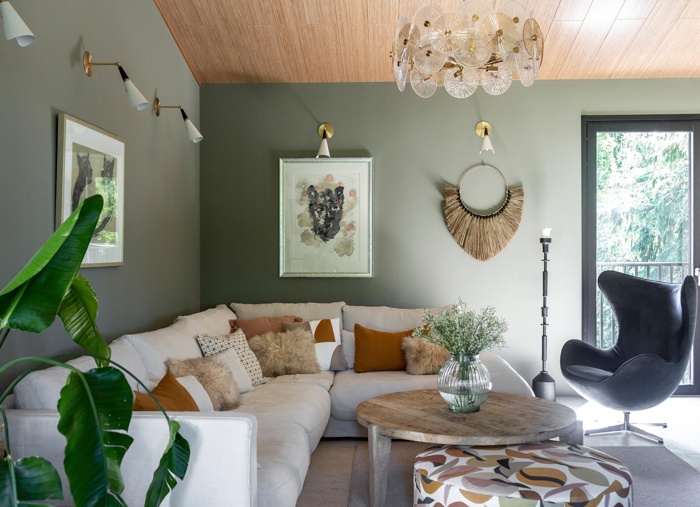 A living room wall painted green, a large lounge sofa, and an Egg chair.