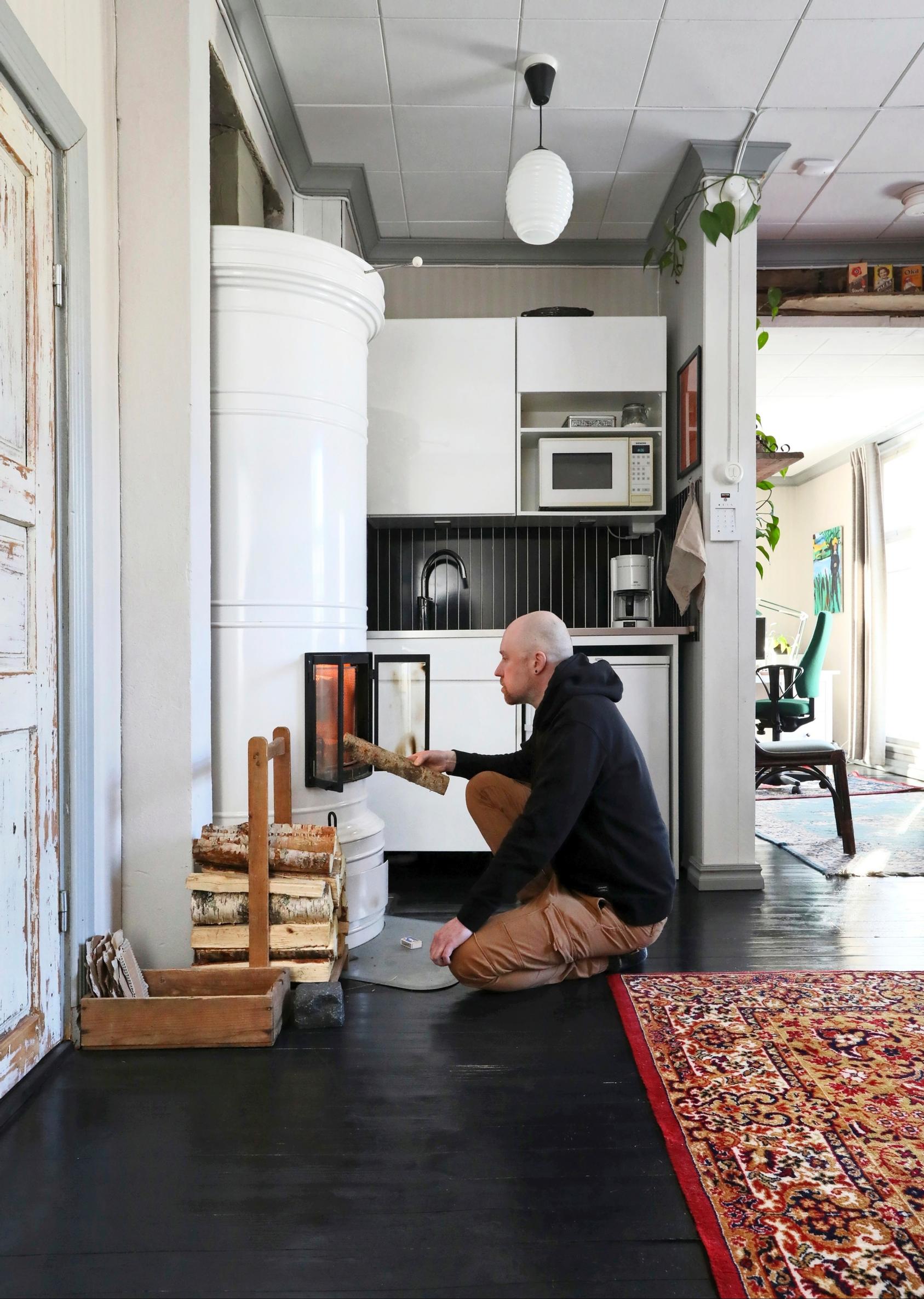 Sami Karjalainen adding firewood to a masonry stove