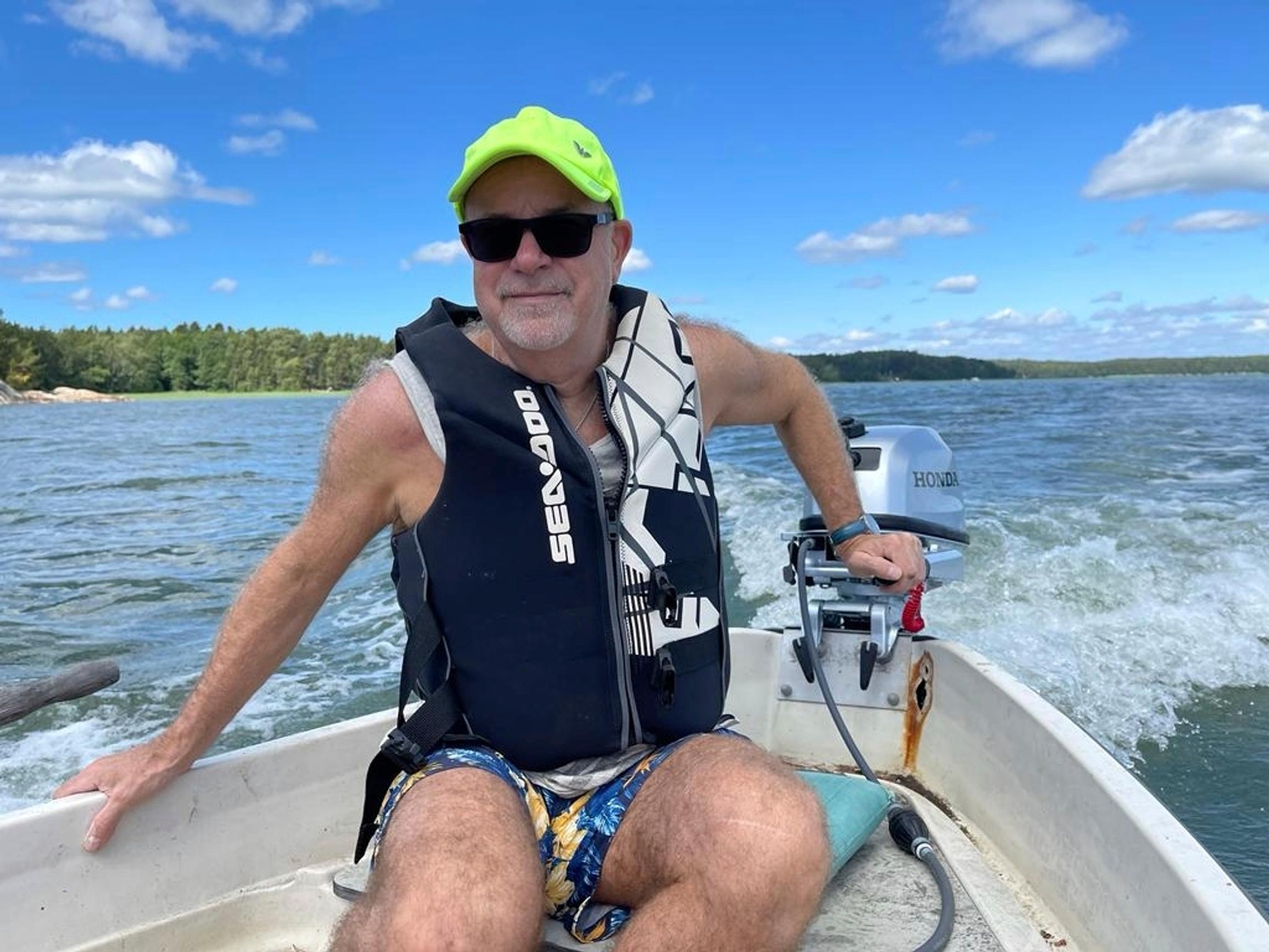 Singer Petri Laaksonen wearing a cap and shorts in a motorboat