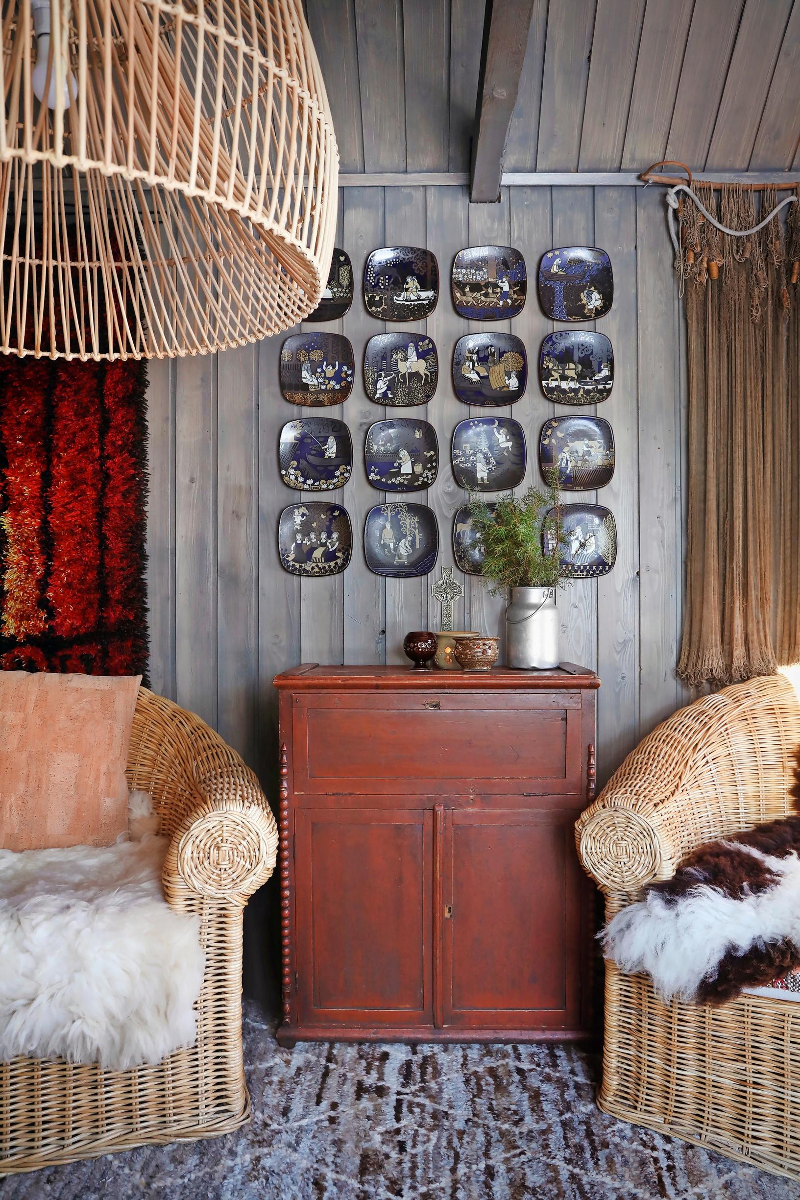 Sheepskins on rattan chairs, reddish dresser and plates on the wall