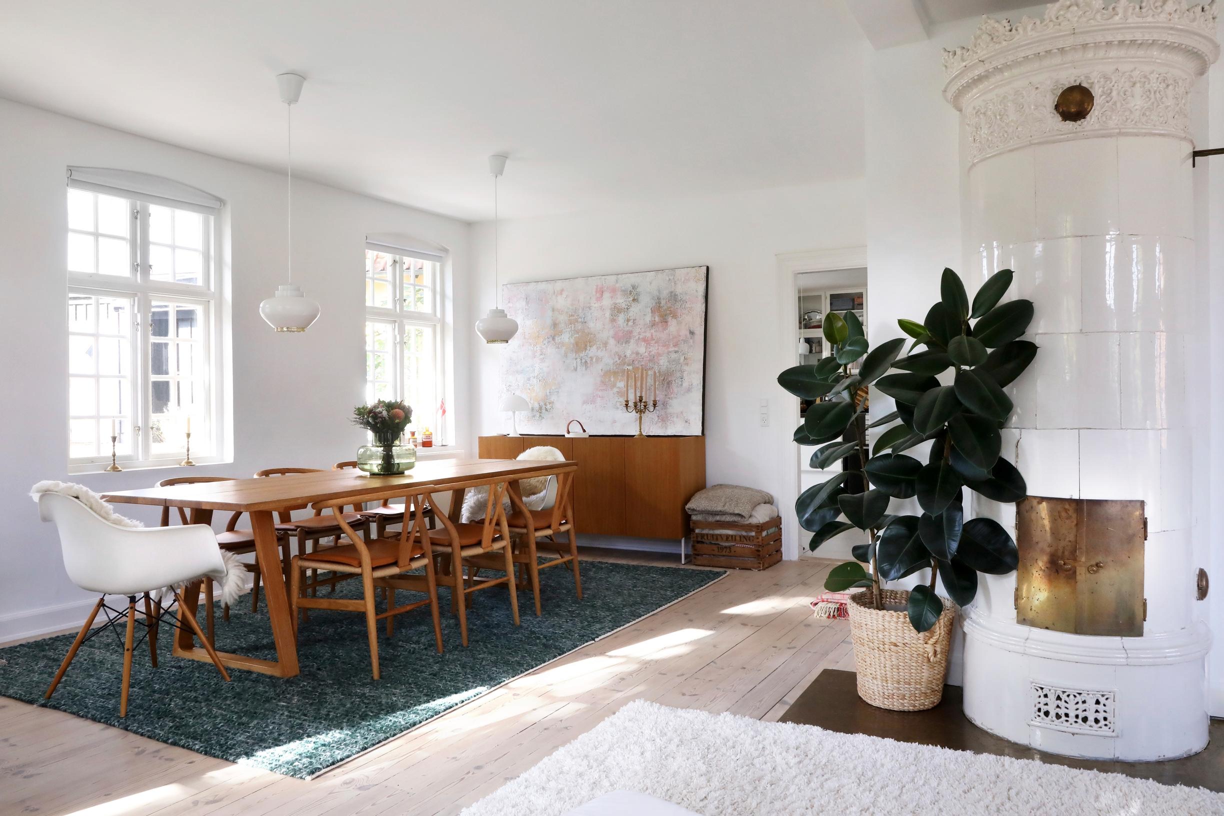 A tile stove, a painting, and designer furniture in the dining area.