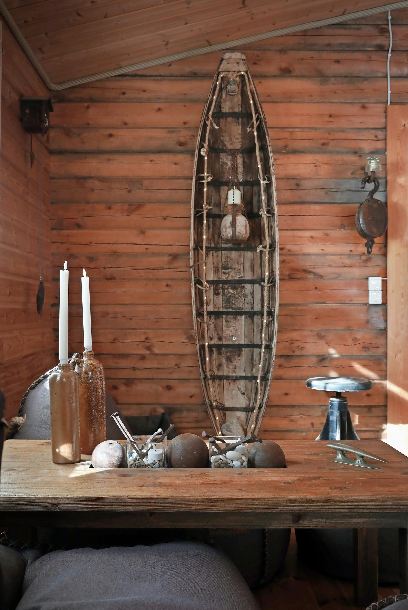 Candles and old fishing gear on a table, with the old sled propped against a log wall.