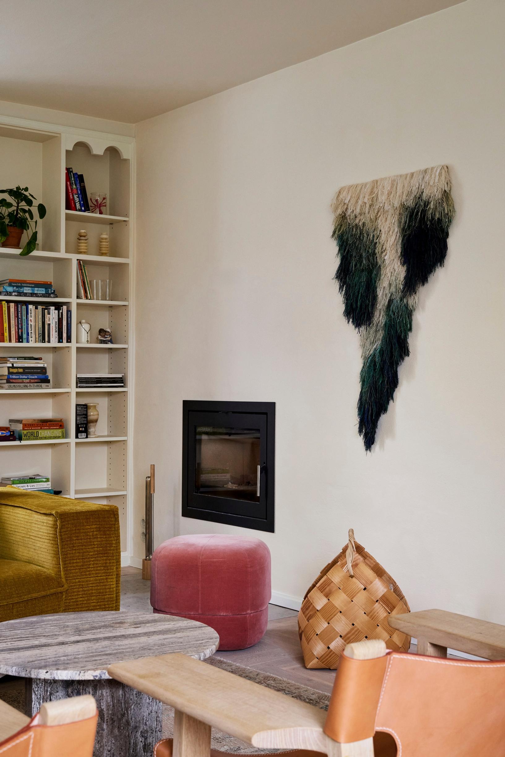 A rya wall hanging next to the living room fireplace