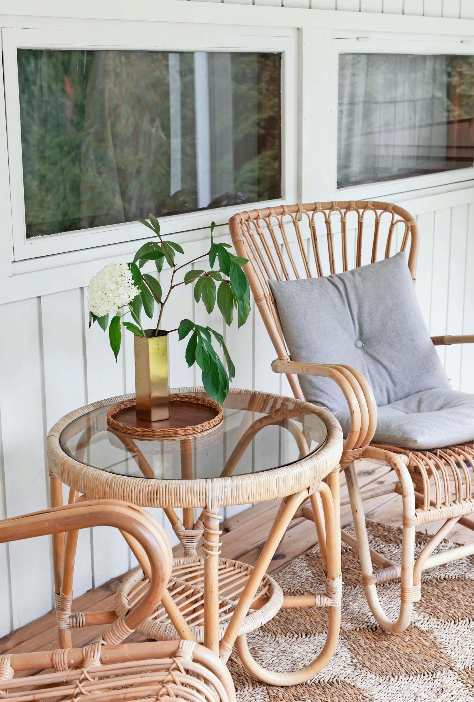 A rattan table and two rattan chairs on the porch.