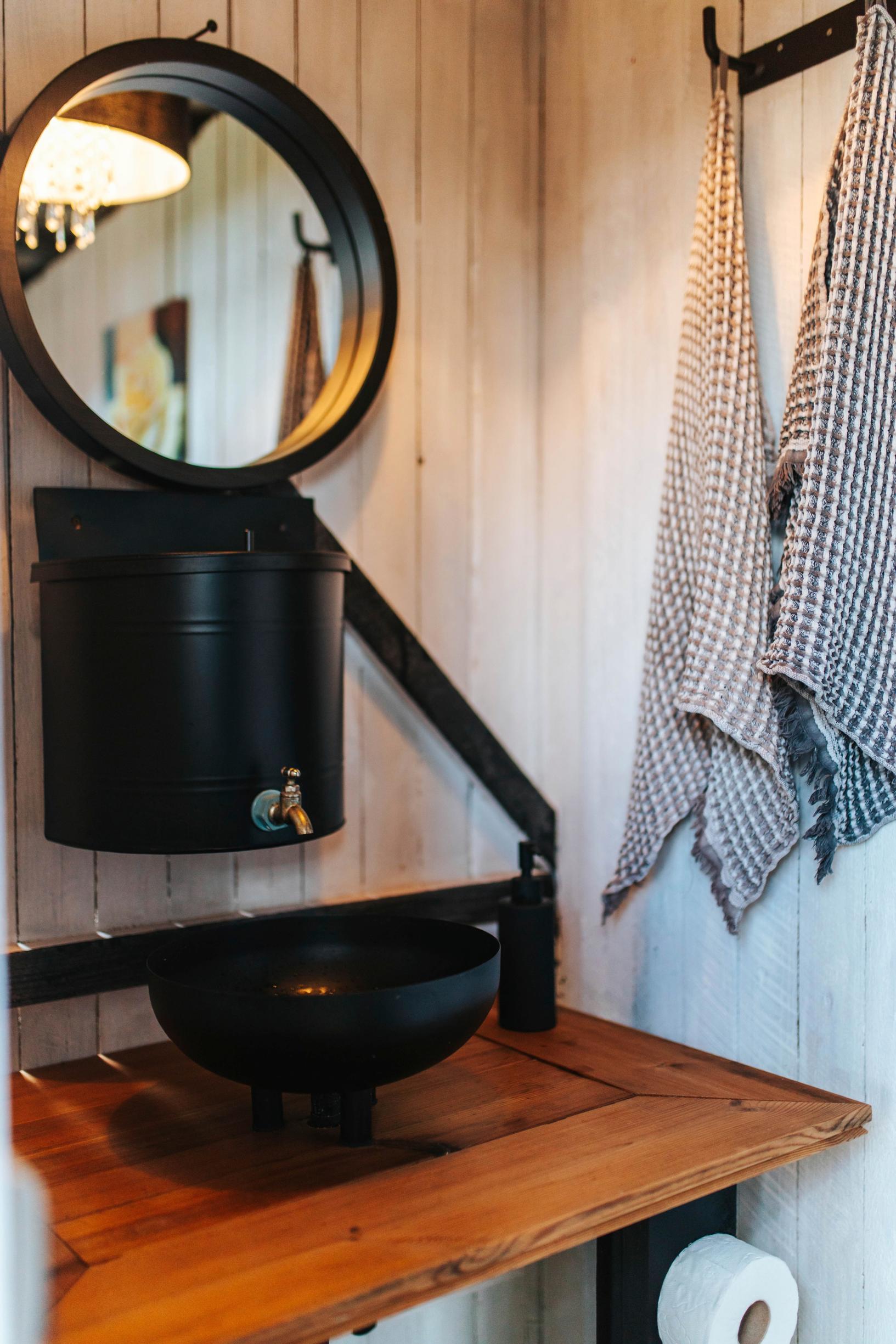 A water tank and washbasin in the outhouse’s hand-washing area
