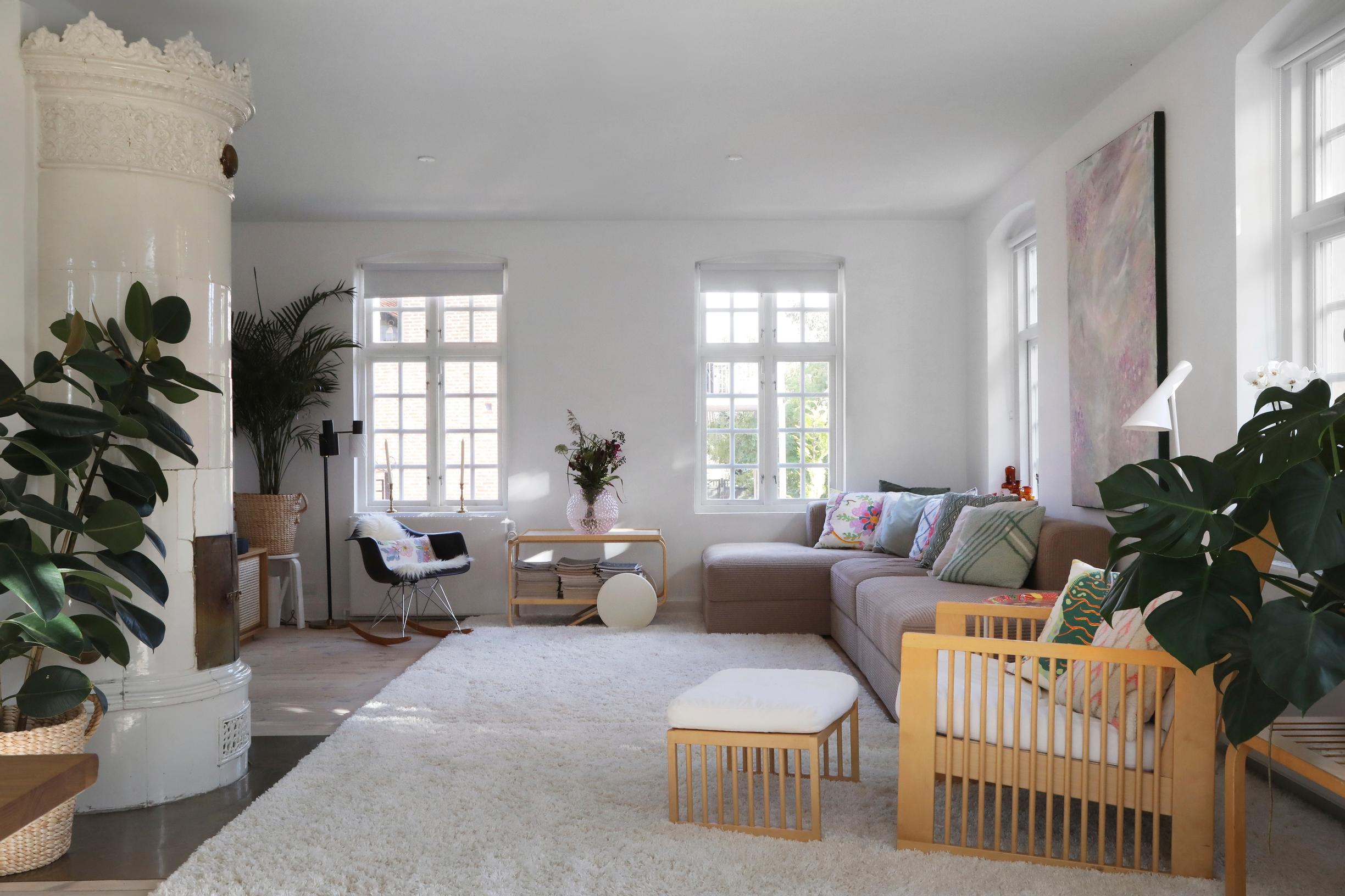 In the living room, mullioned windows, a tile stove, a sofa, and several armchairs