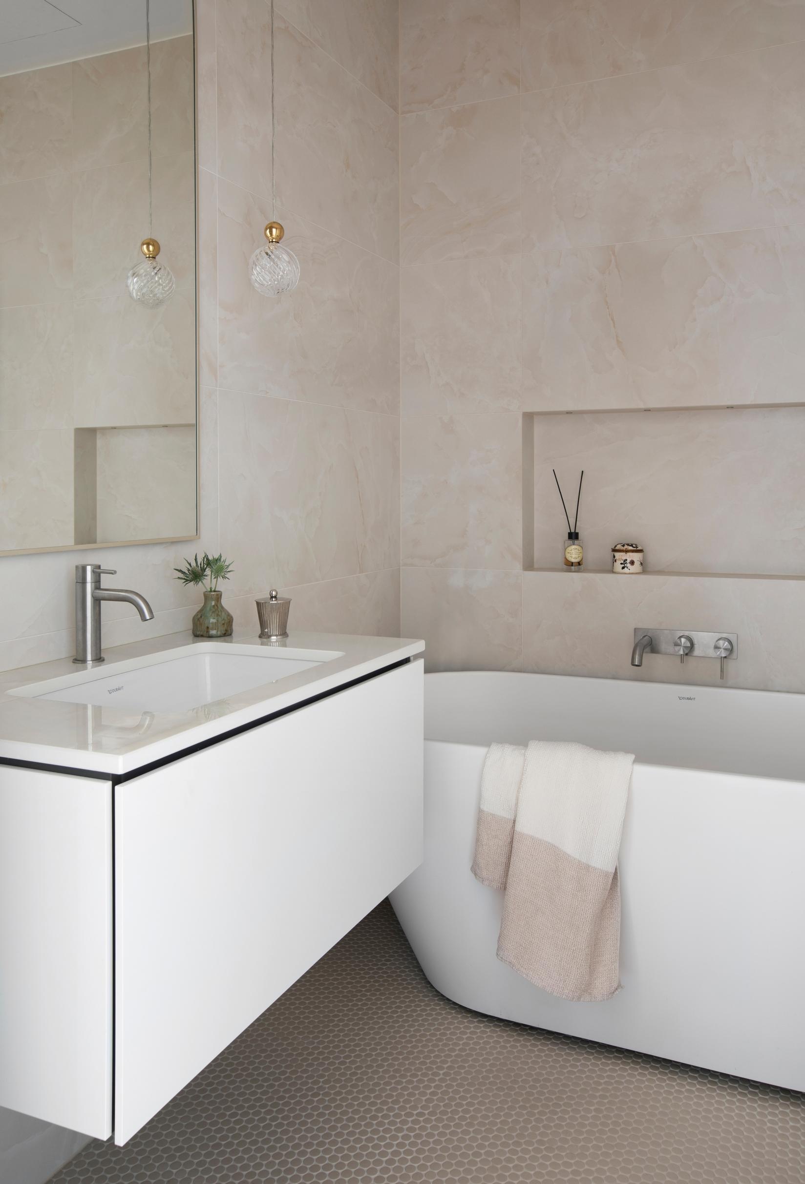 Light and serene bathroom with a tub and Italian tiles.